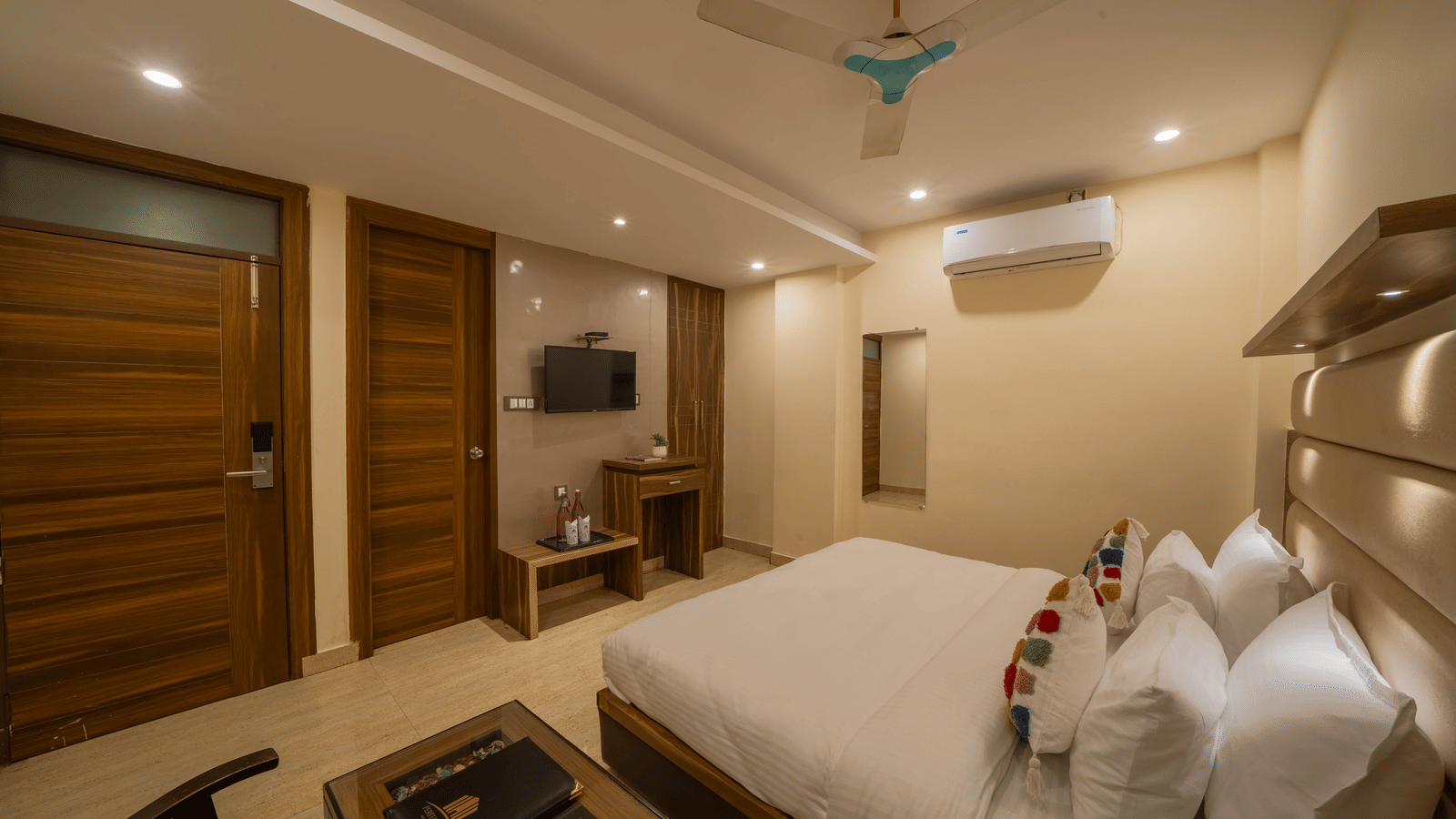 Well-lit hotel room showing a large bed, ceiling fan, and television on the wall - Perfectstayz Premium at Har Ki Pauri Road (Ganga Heights)