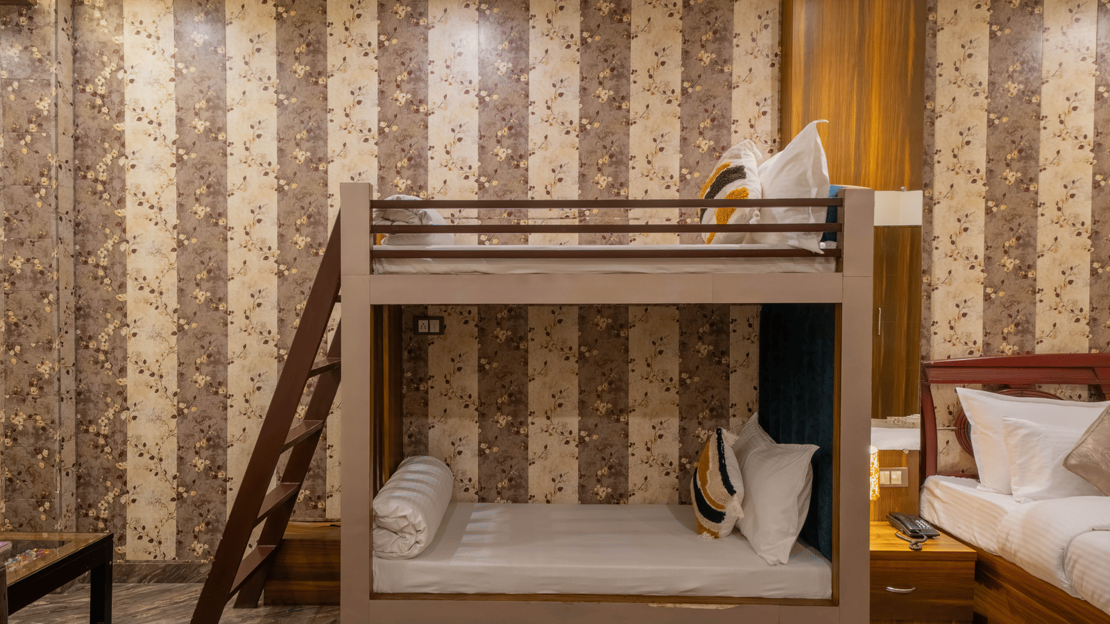 View of bunk beds and a side table with a lamp, set against patterned wallpaper - Perfectstayz Premium at Har Ki Pauri Road (Ganga Heights)