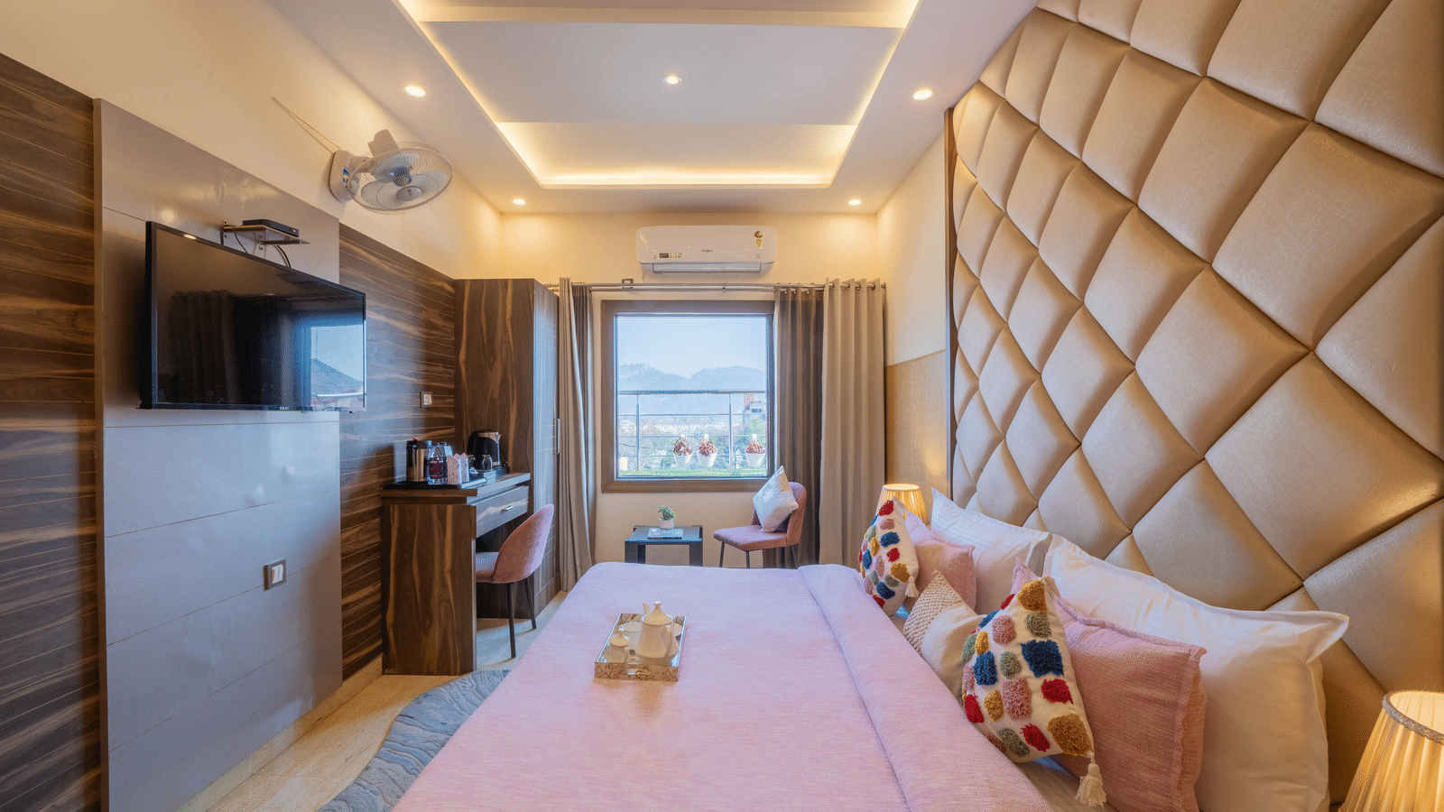Bright room with a pink-themed bed, tufted headboard, and large window view - Perfectstayz Premium at Har Ki Pauri Road (Ganga Heights)