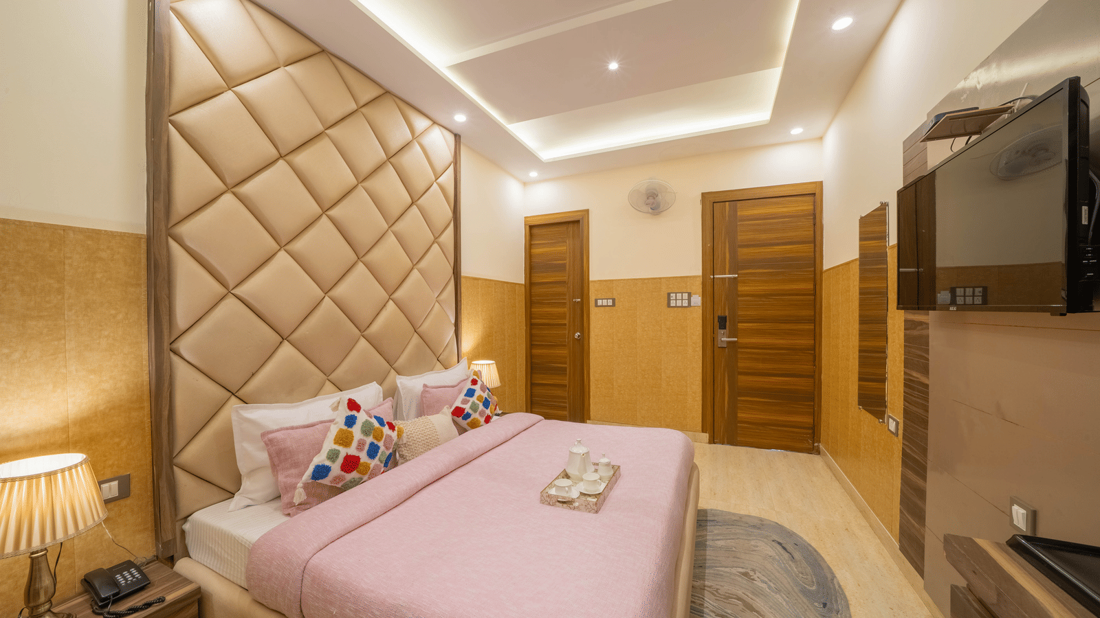 Wide view of a spacious hotel room with bright lighting, a pink bed, and a cushion headboard - Perfectstayz Premium at Har Ki Pauri Road (Ganga Heights)