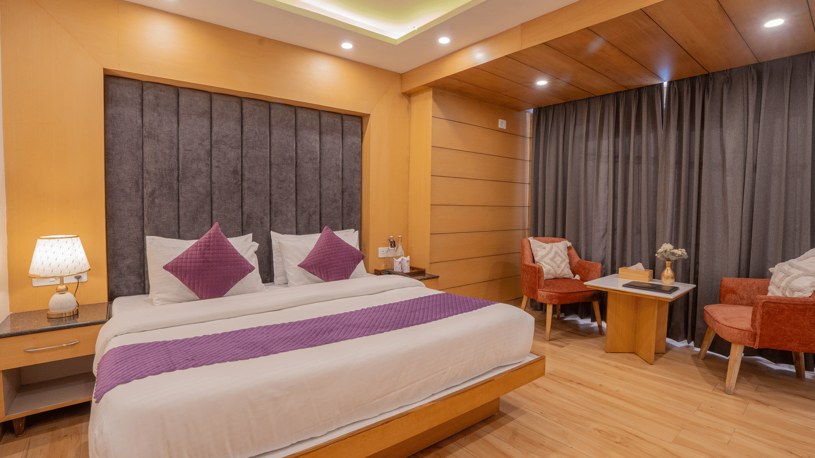 A bedroom with a bed, chairs, and curtains at Perfectstayz Premium at Mall Road Hotel Super, Mussoorie.