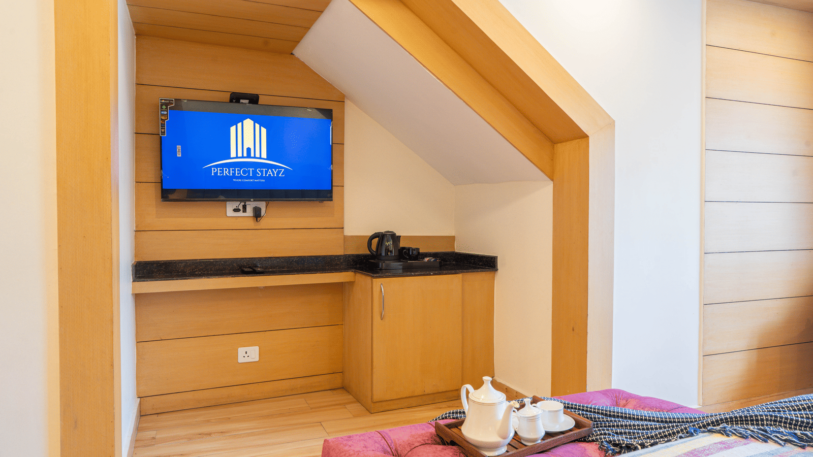 A television setup with seating near a bed at Perfectstayz Premium at Mall Road Hotel Super, Mussoorie.