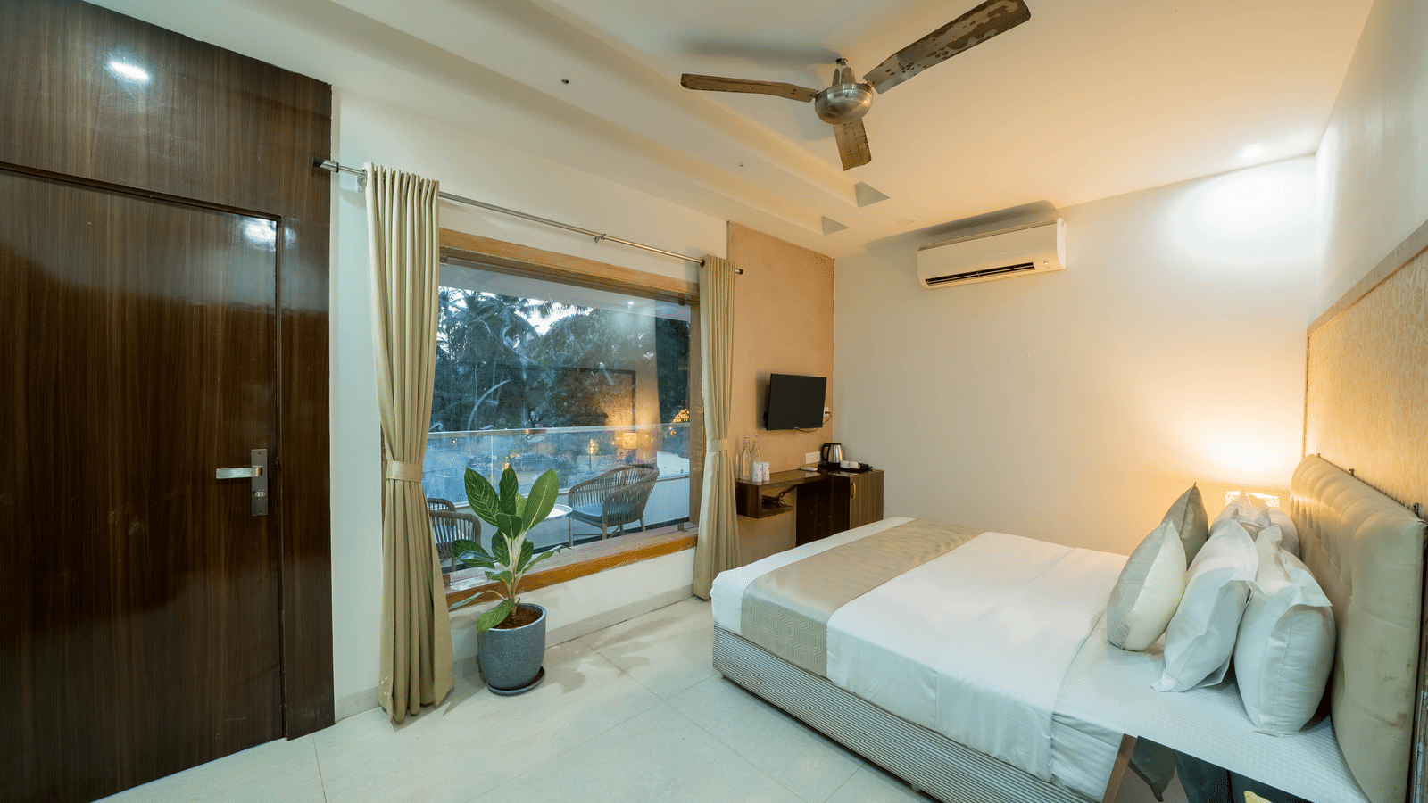 A clean, spacious double bed room at Perfectstayz Premium Goa Continental, featuring a large bed, simple decor, and a window with a pool view.