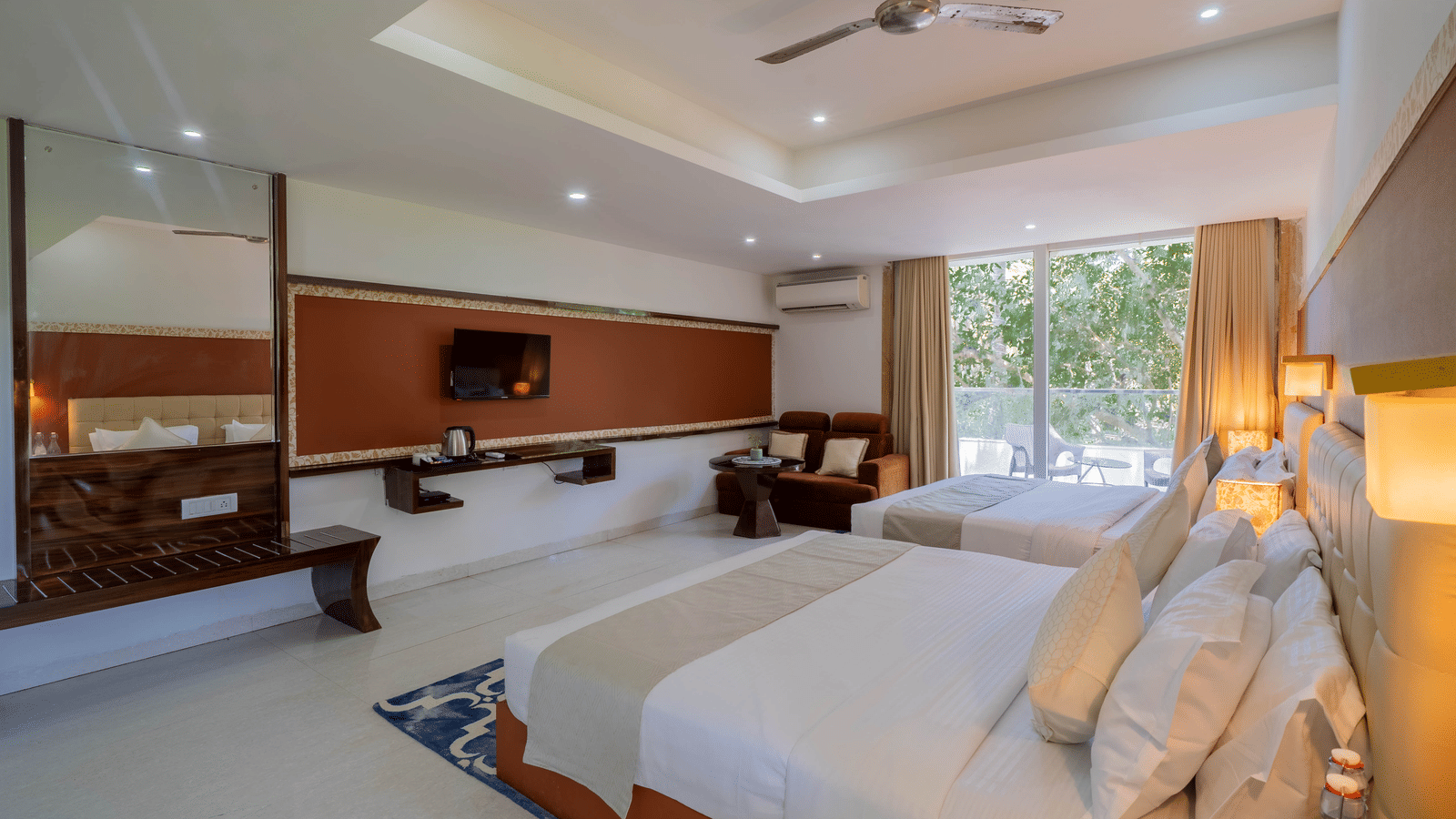 A large, bright hotel bedroom featuring 2 double beds, stylish modern wooden furniture, and ceiling fans - Perfectstayz Premium Goa Continental