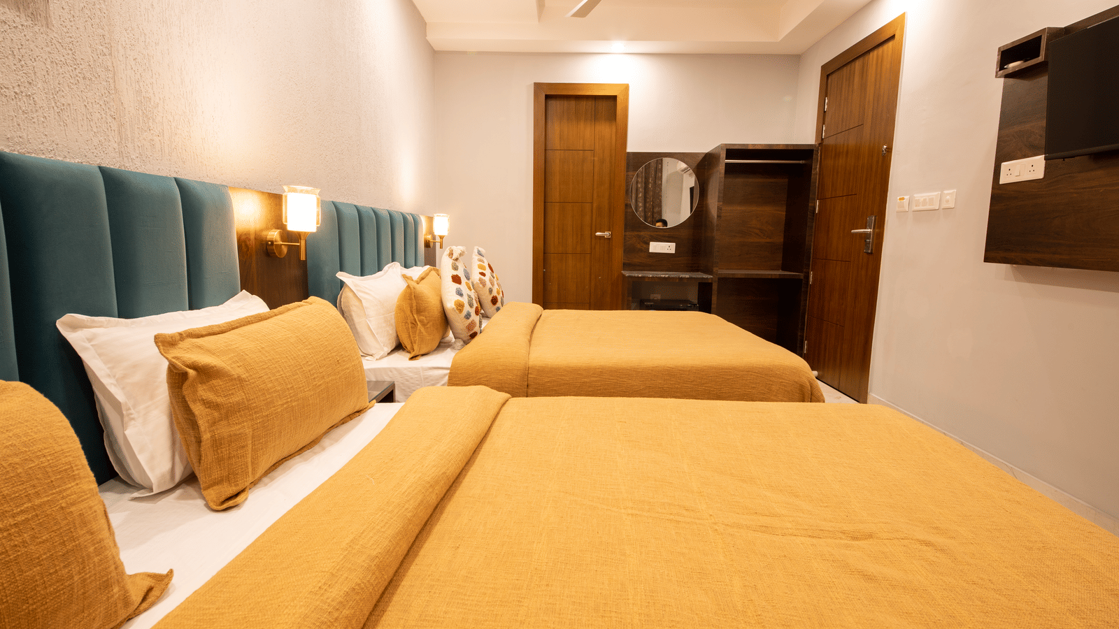 A bedroom with 2 king size beds, wooden vanity, and lighting at Perfectstayz Premium Laxmi Heritage.