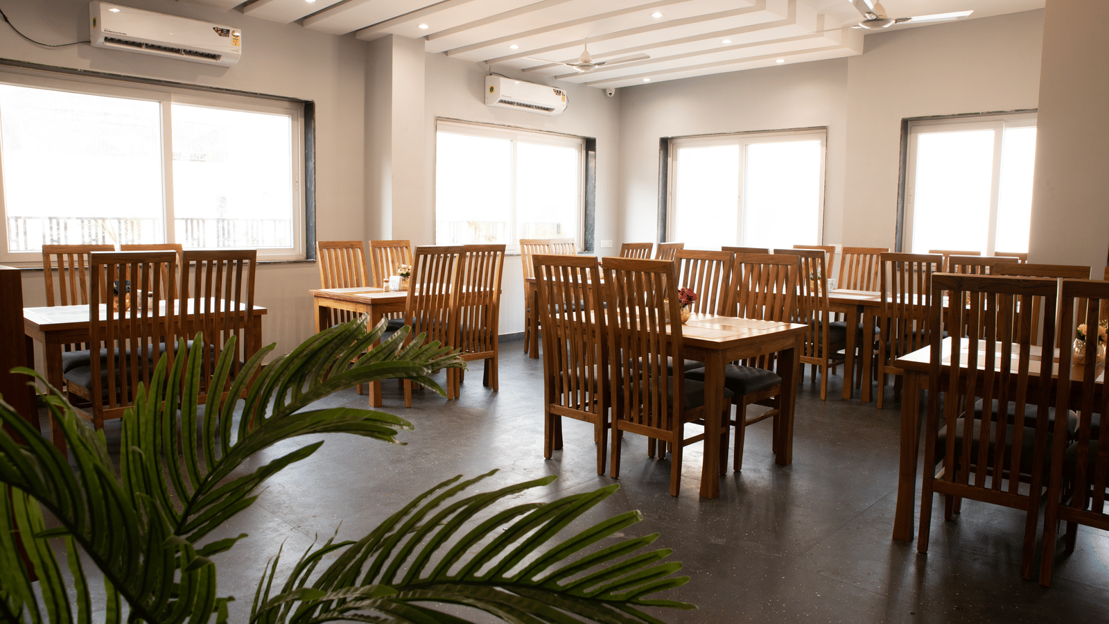A dining area with tables, chairs, and a potted plant at Perfectstayz Premium Laxmi Heritage.