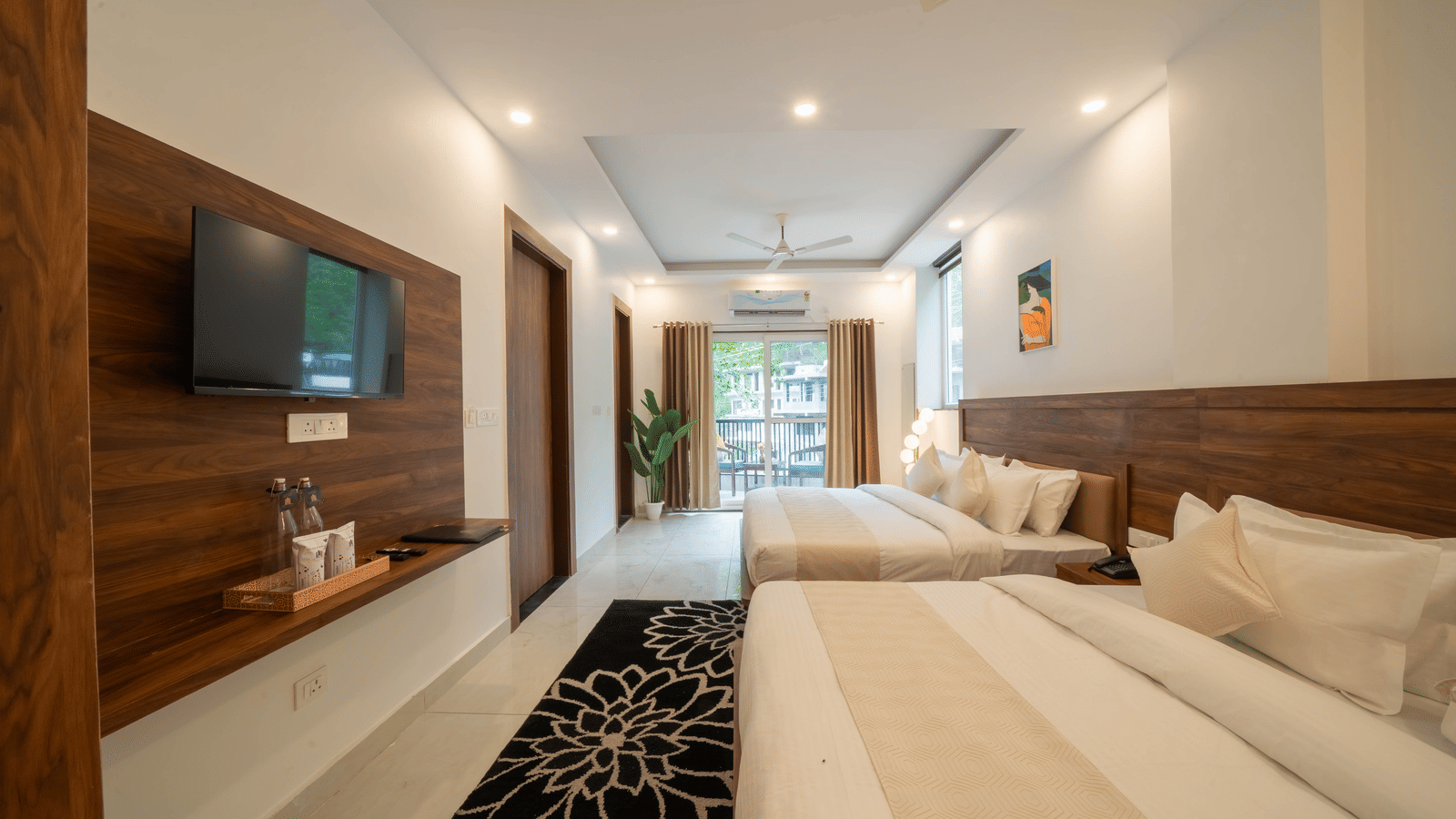 A room with 2 separate beds, a wall-mounted television, a wall panel with shelving, and a rug on the floor in Perfectstayz Premium Mystic Falls, Rishikesh.