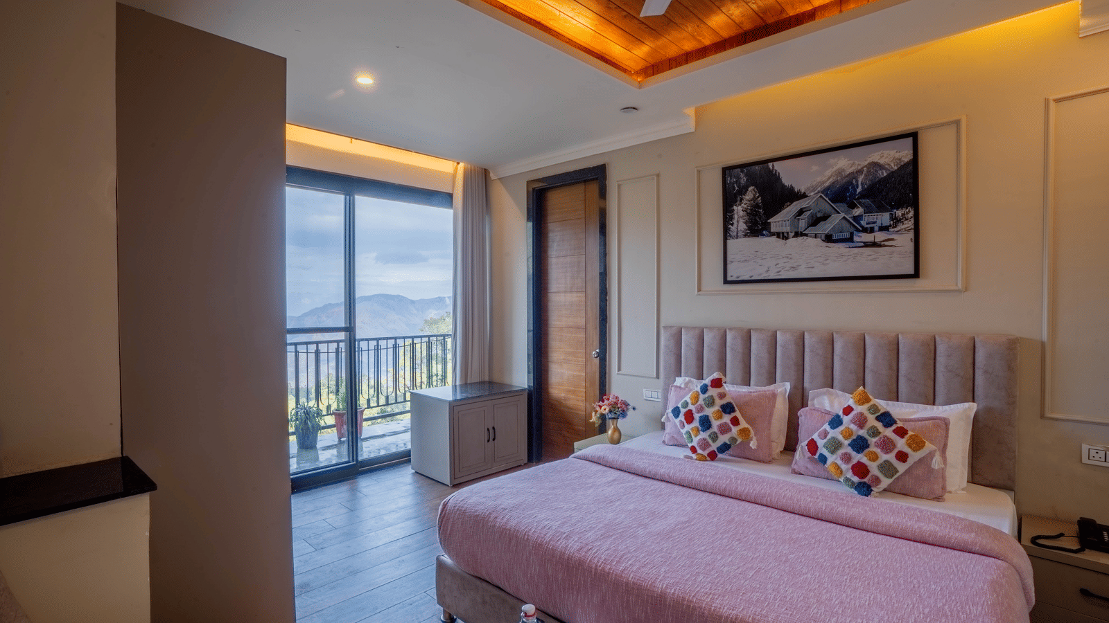 A wide-angle shot of the Family Suite With Shared Balcony & Valley View featuring a double bed with neatly-arranged cushions and a balcony in the side at Perfectstayz Premium Westend Mall Road, Mussoorie.