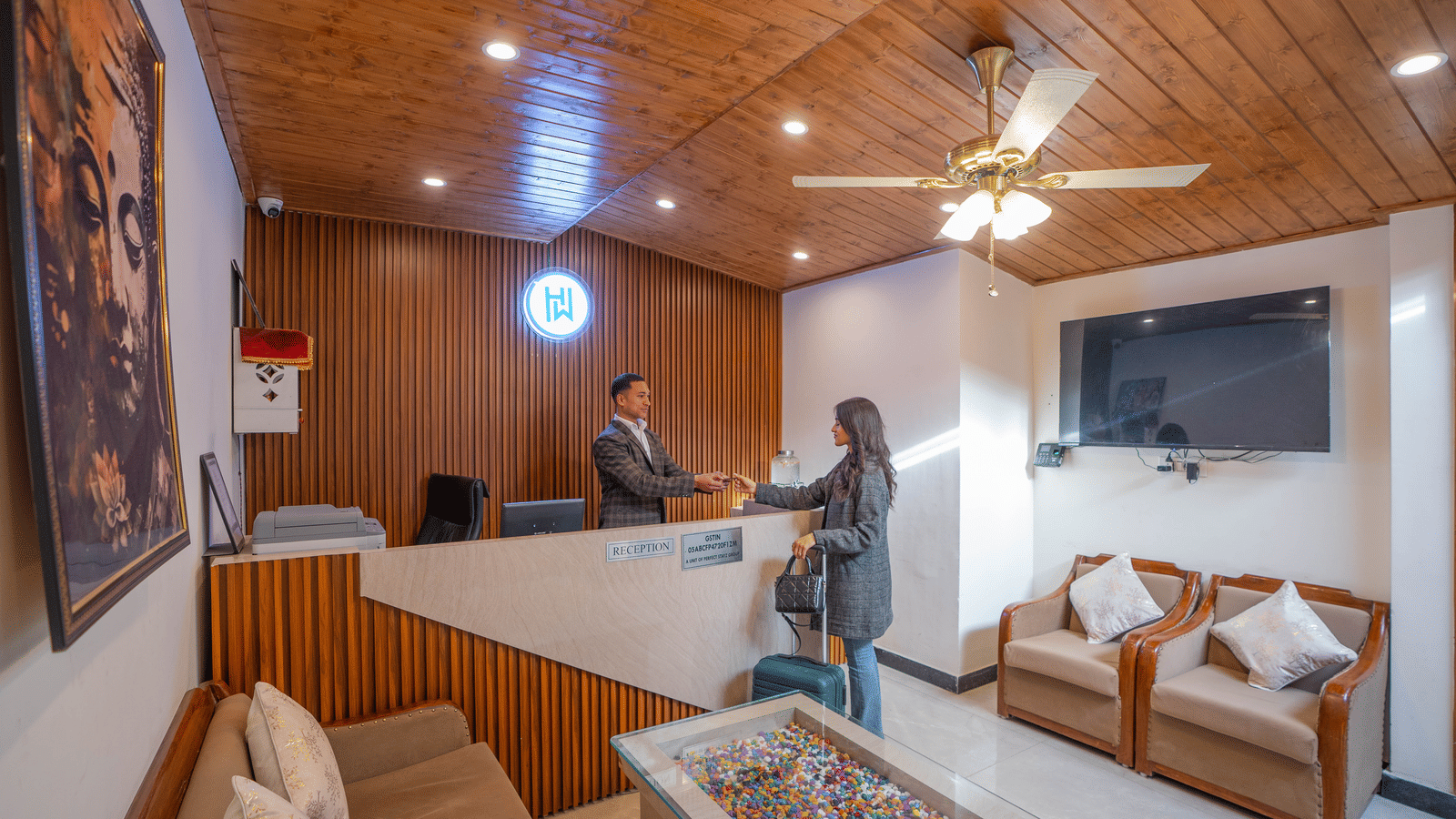 A wide-angle shot of the lobby area of the Perfectstayz Premium Westend Mall Road, Mussoorie, with a staff member giving the room key card to a female guest.