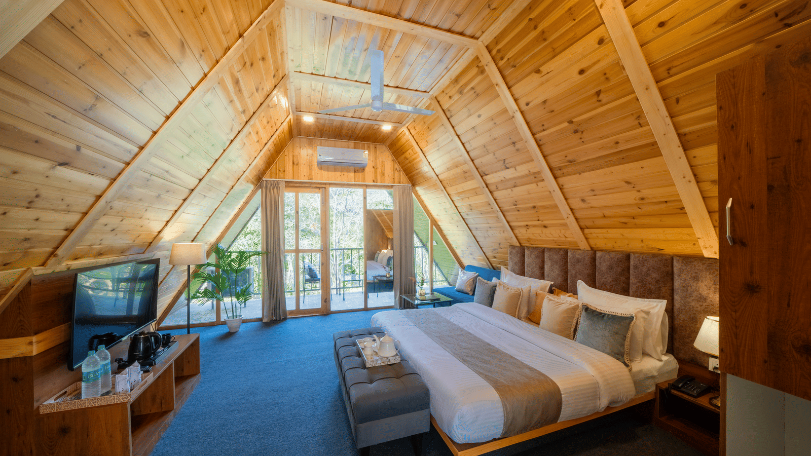 The A-frame bedroom at Perfect Stayz The Jungle Resort contains a bed, a television, and a wooden ceiling.