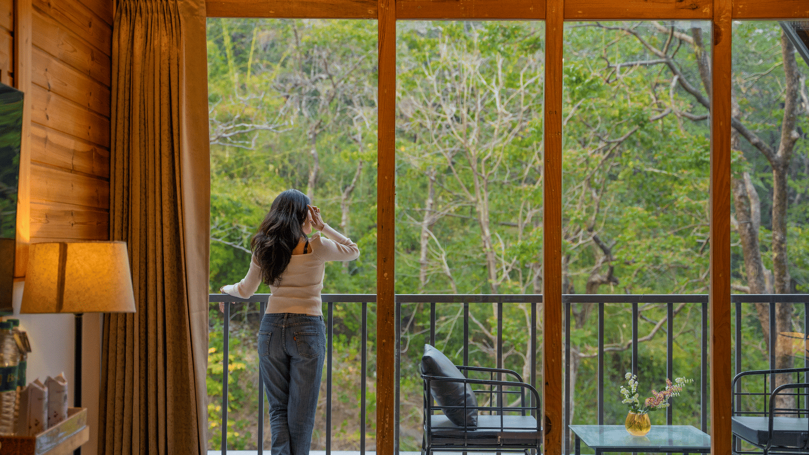 A person stands on a balcony at Perfect Stayz The Jungle Resort, looking towards the tree