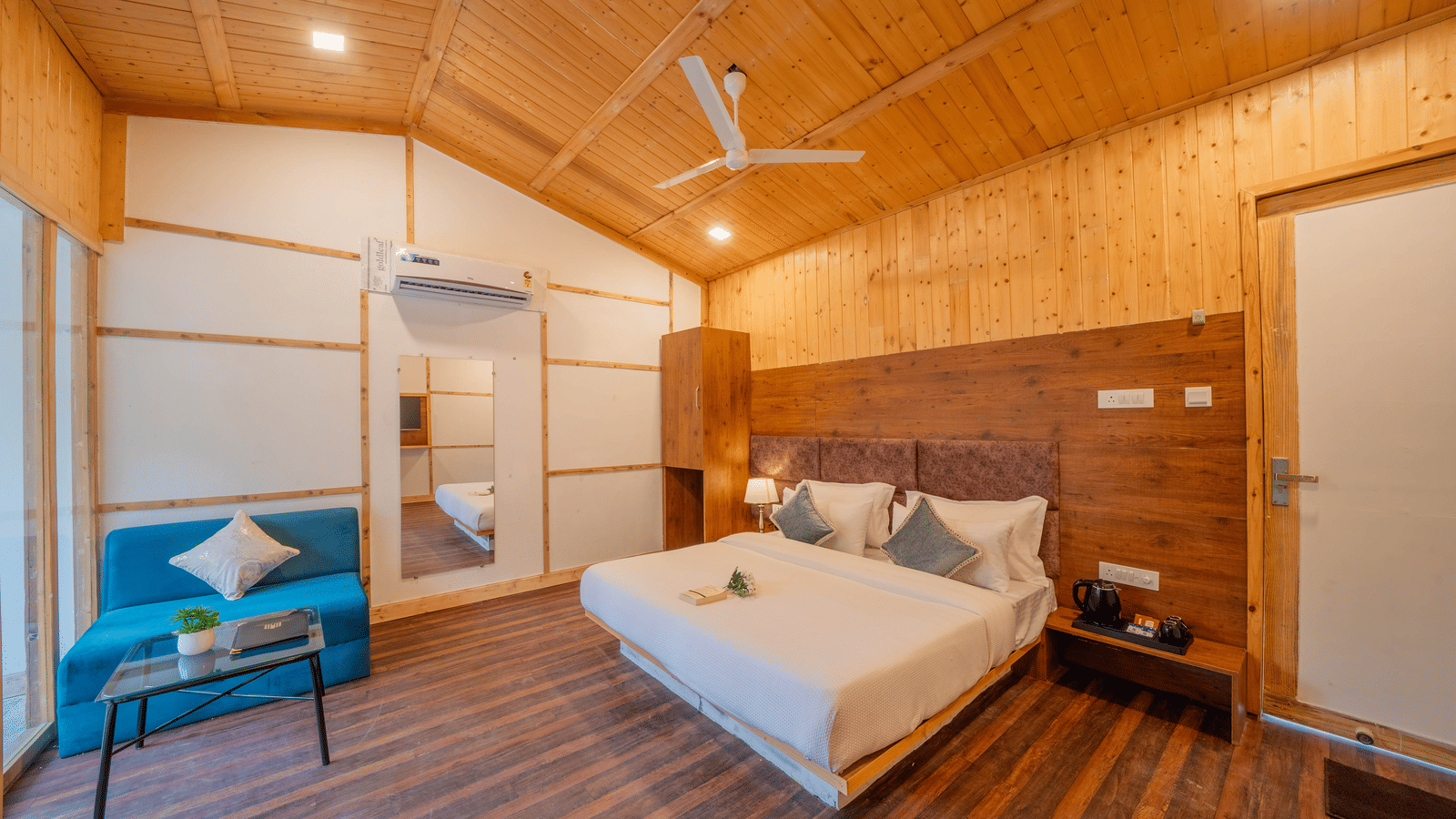 A loft bedroom at Perfect Stayz The Jungle Resort features a bed, a sofa, and wooden flooring.