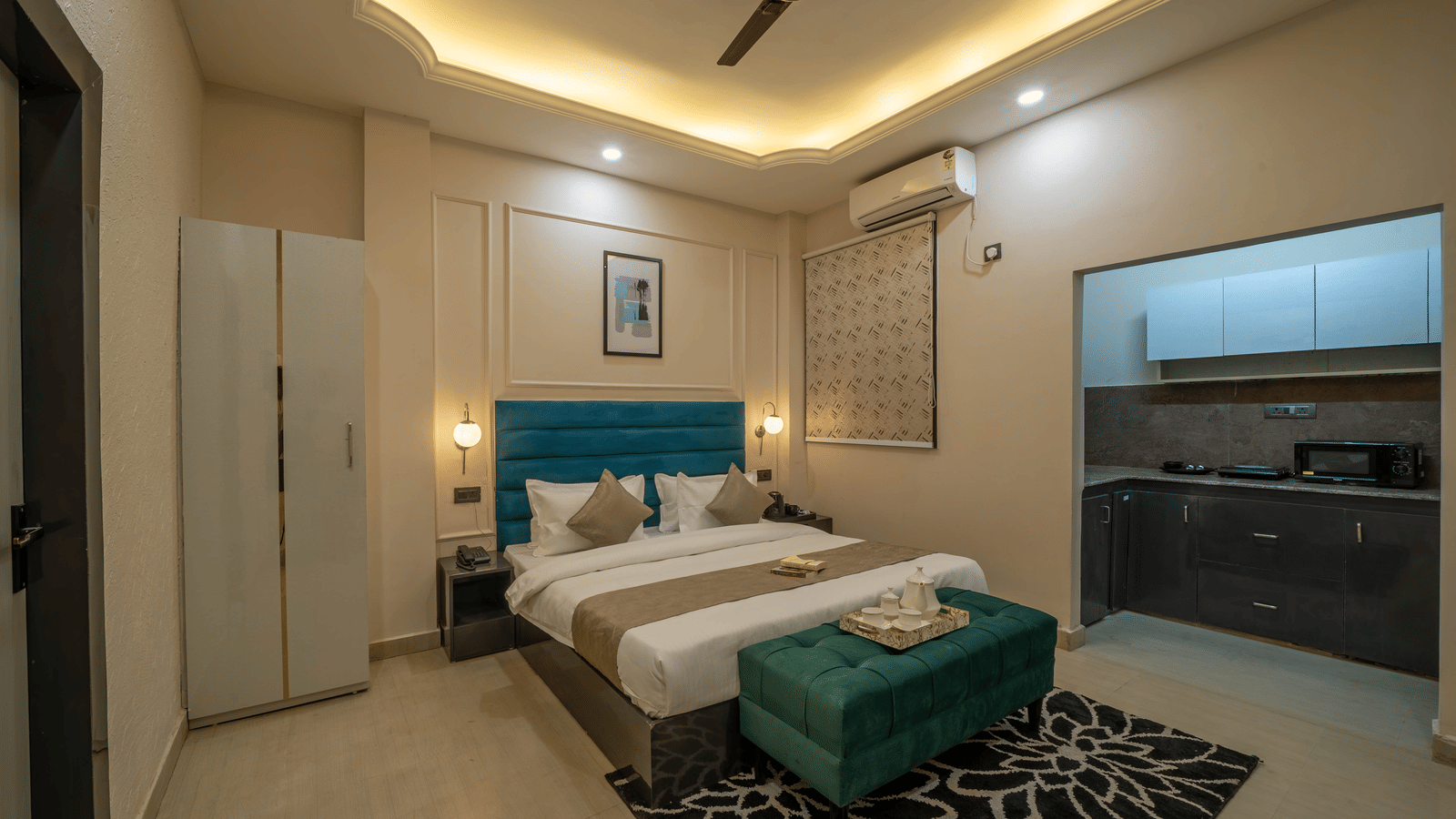 A room showing the sleeping area next to an open kitchenette with an overhead cabinetry - Perfectstayz Value Aalaya Suites, Haridwar
