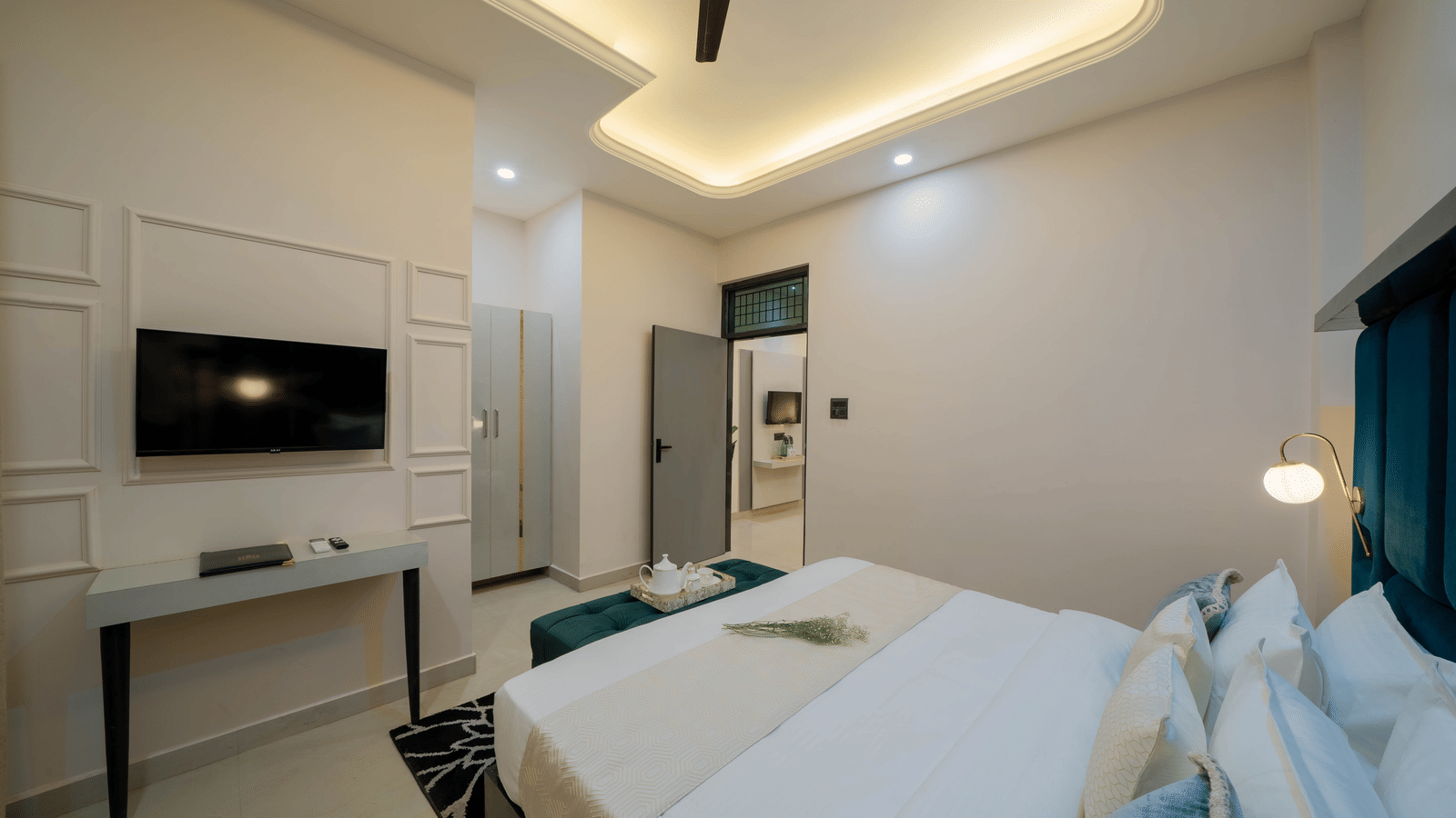 Modern bedroom with a large bed, a work station, a ceiling fan, and a TV mounted on the wall - Perfectstayz Value Aalaya Suites, Haridwar