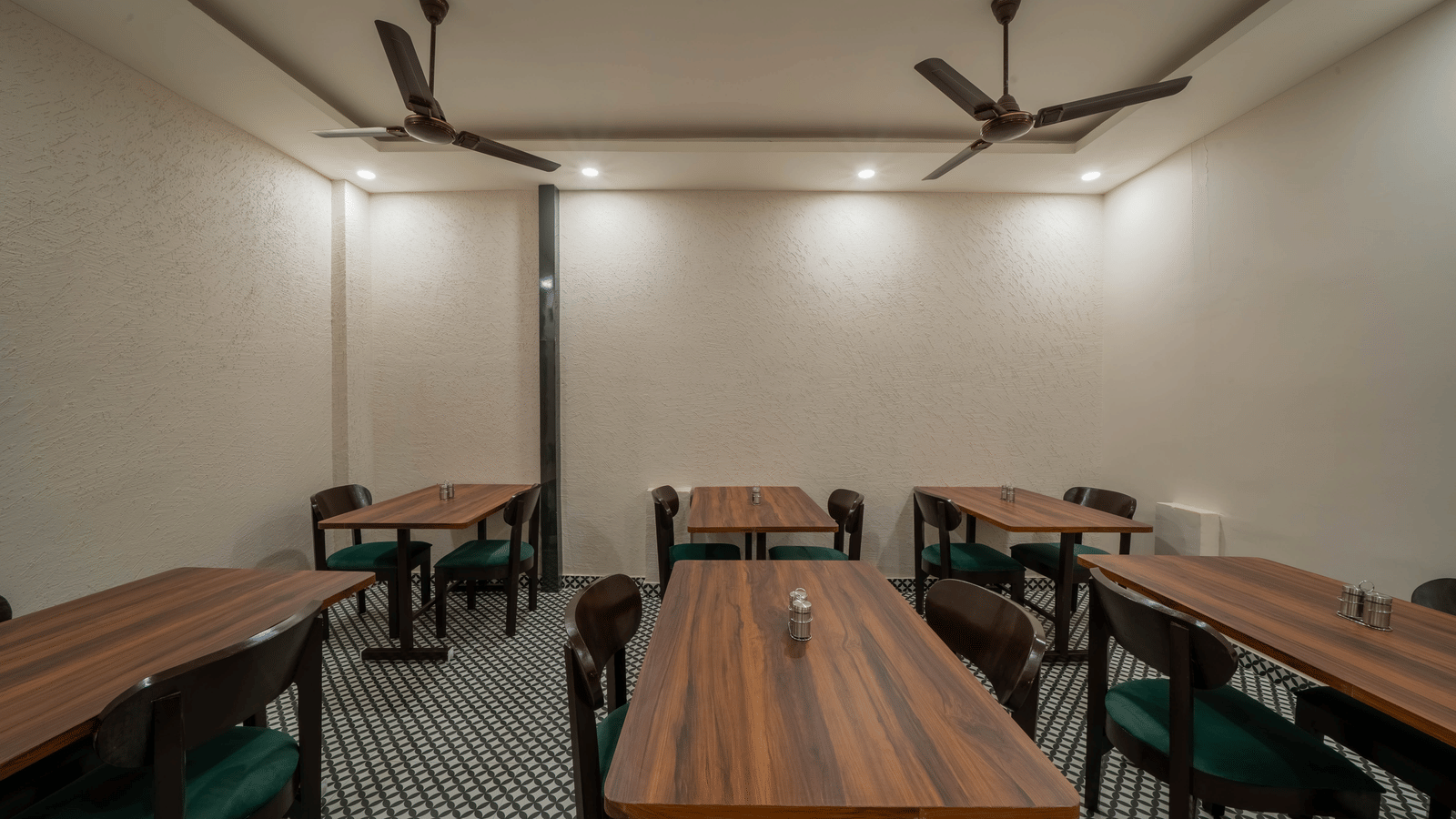 Spacious dining area with multiple dark wooden tables and chairs, a simple white ceiling with a fan, and bright lighting - Perfectstayz Value Aalaya Suites, Haridwar