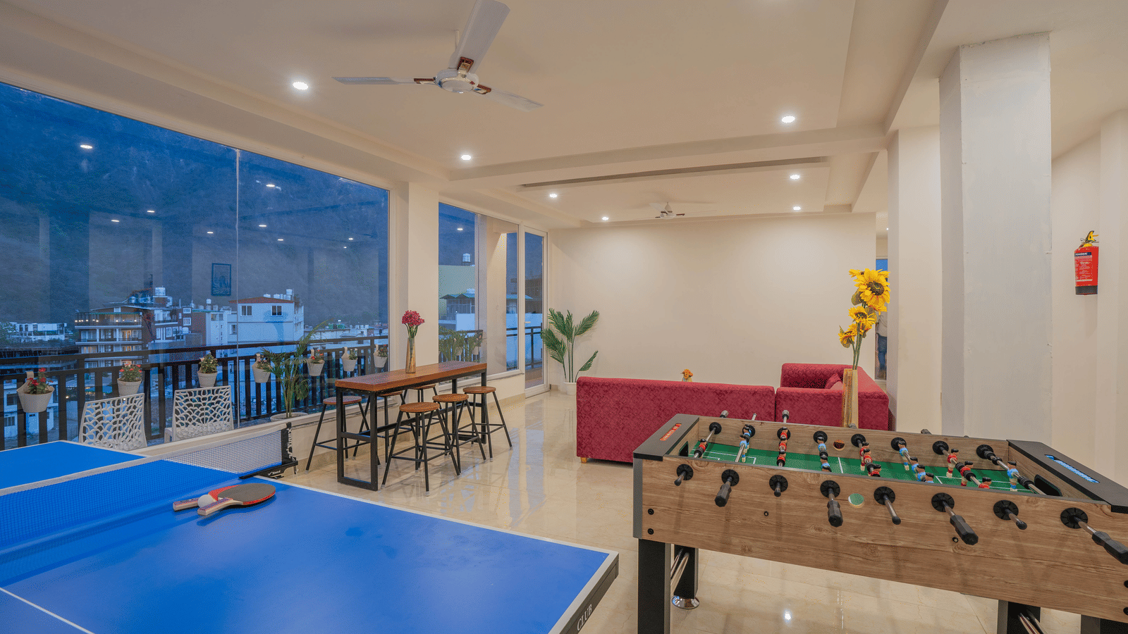 An indoor games room at Perfectstayz Value Alpine Retreat, Rishikesh featuring table tennis board, foosball, and seating area.
