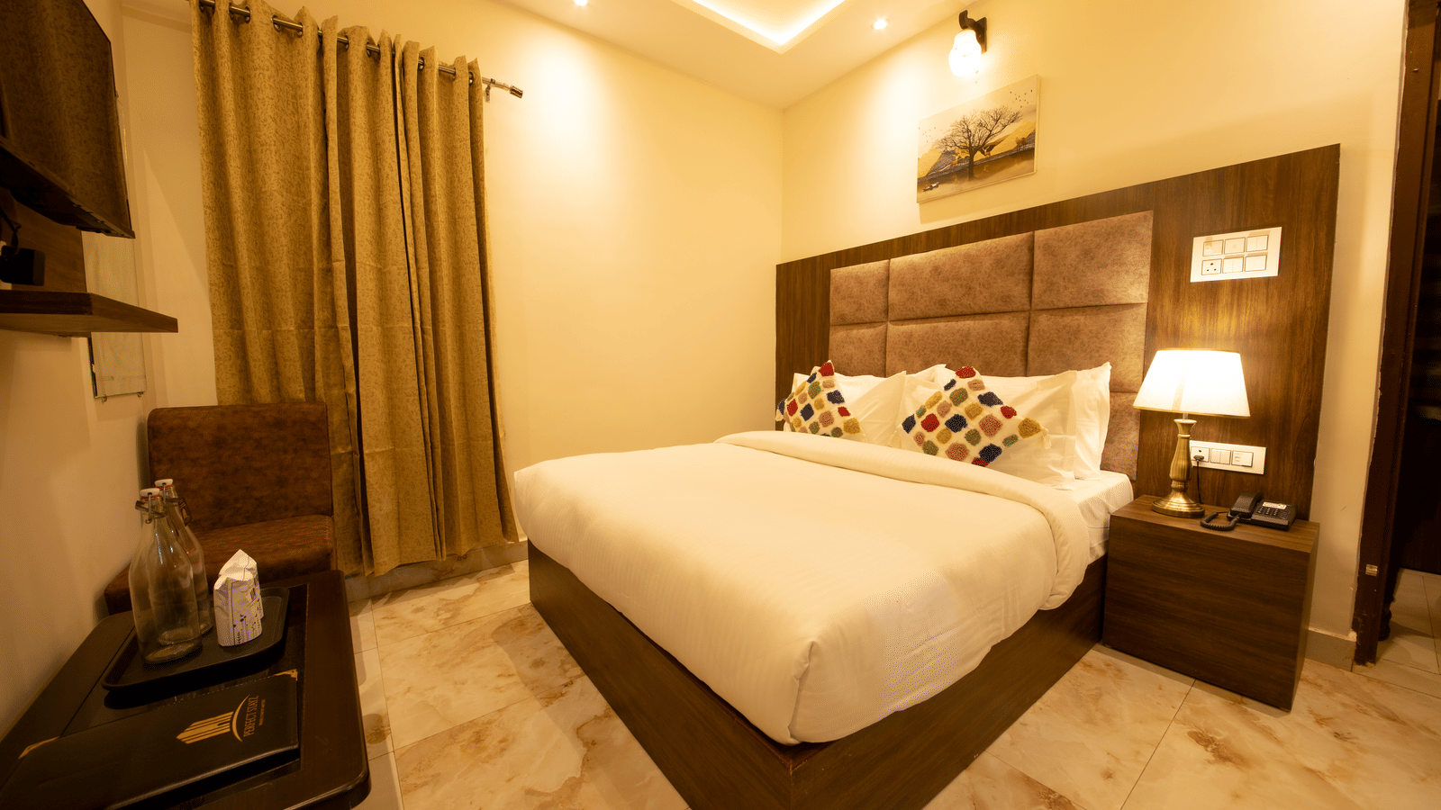 A wide-angle shot of the double bed in the Standard Room with a coffee table in front of it at Perfectstayz Value Dhruv Nanda, Haridwar.