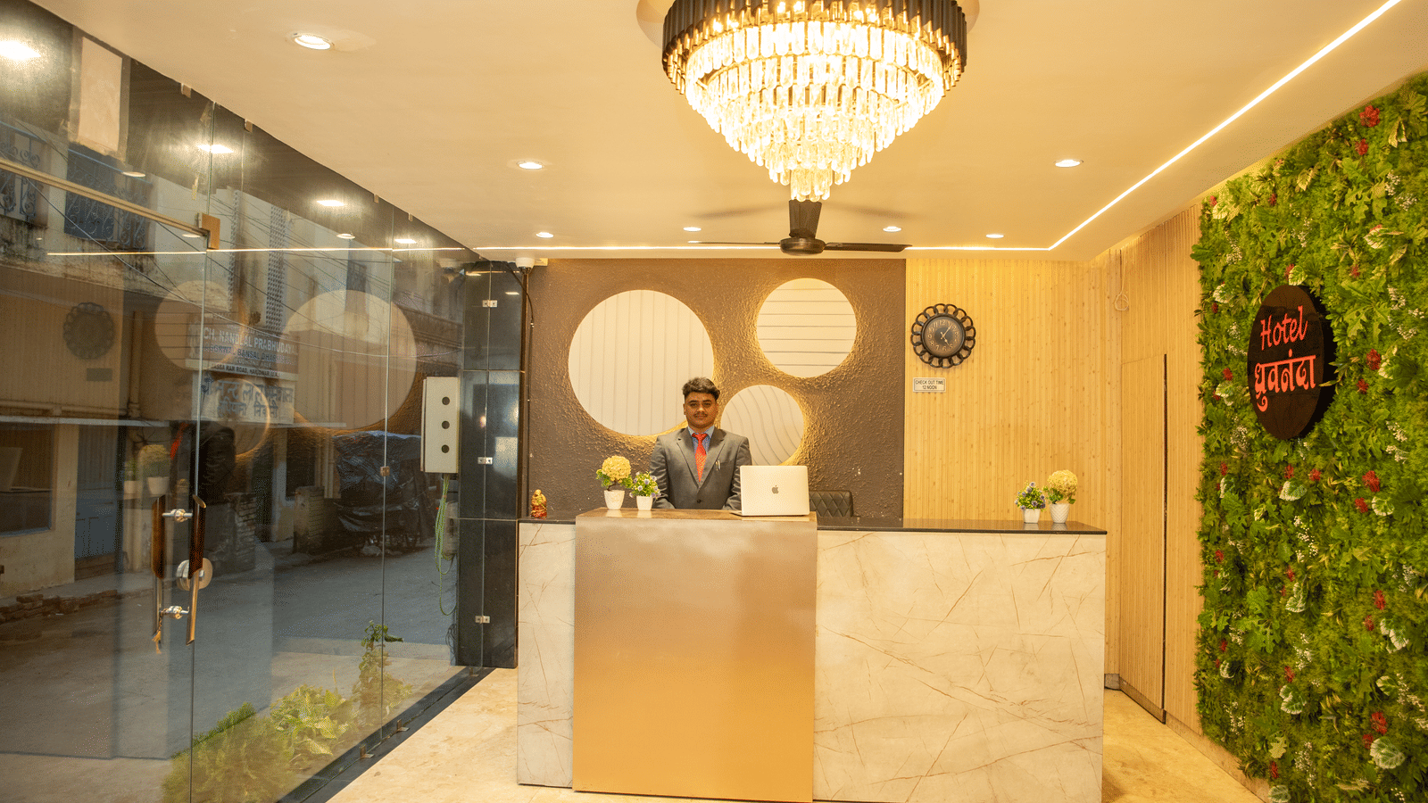 A staff member dressed in business formals standing behind the reception desk at Perfectstayz Value Dhruv Nanda.