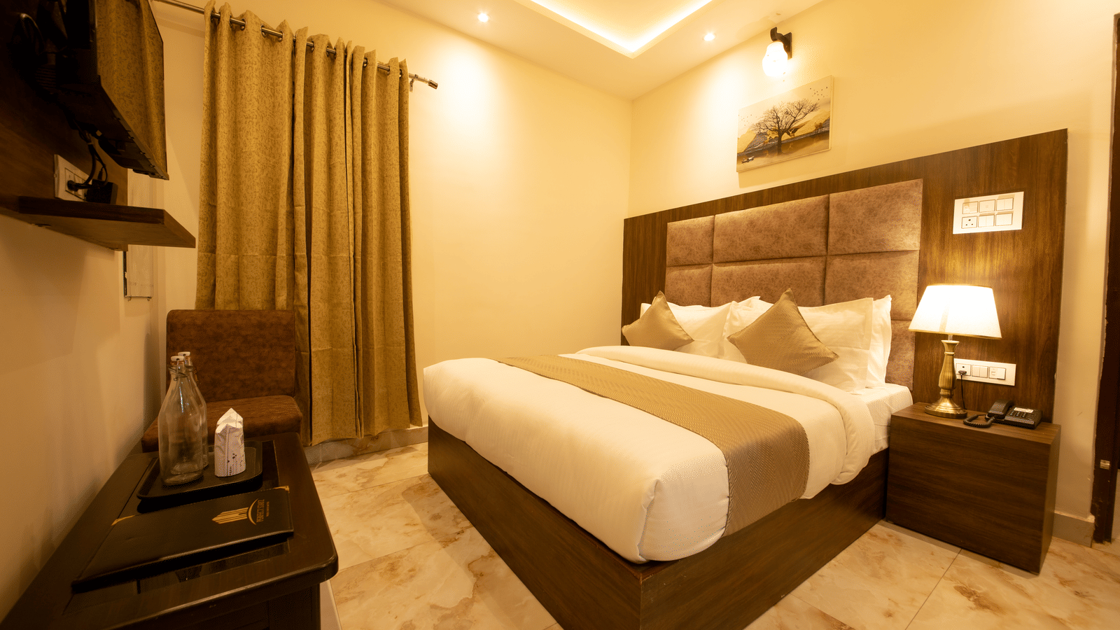 Corner view of the Deluxe Room with warm lighting featuring a wall-mounted television at the Perfectstayz Value Dhruv Nanda.