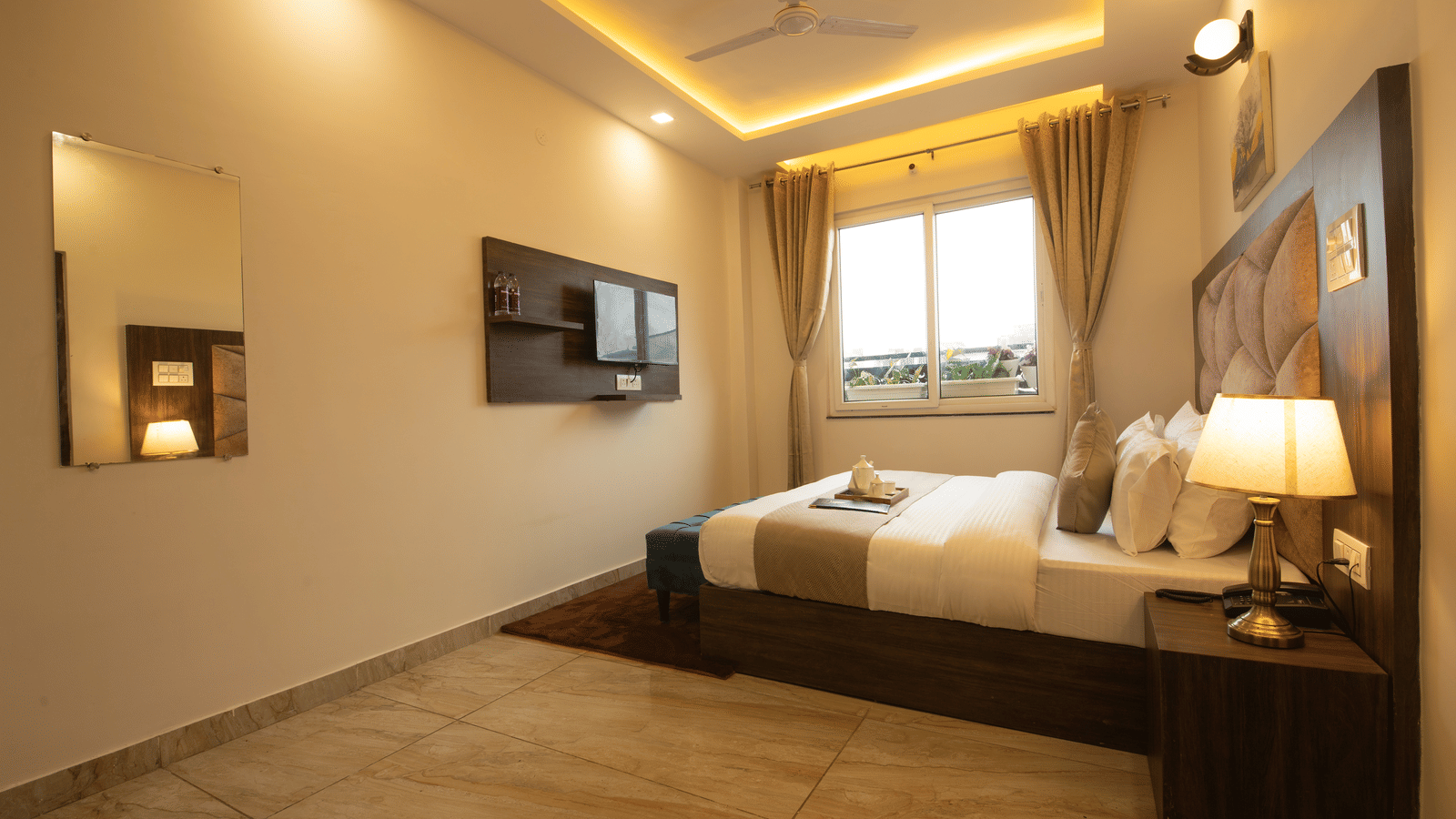 Side-angle shot of the Executive Room featuring a window beside it along with false ceiling in the room at Perfectstayz Value Dhruv Nanda.