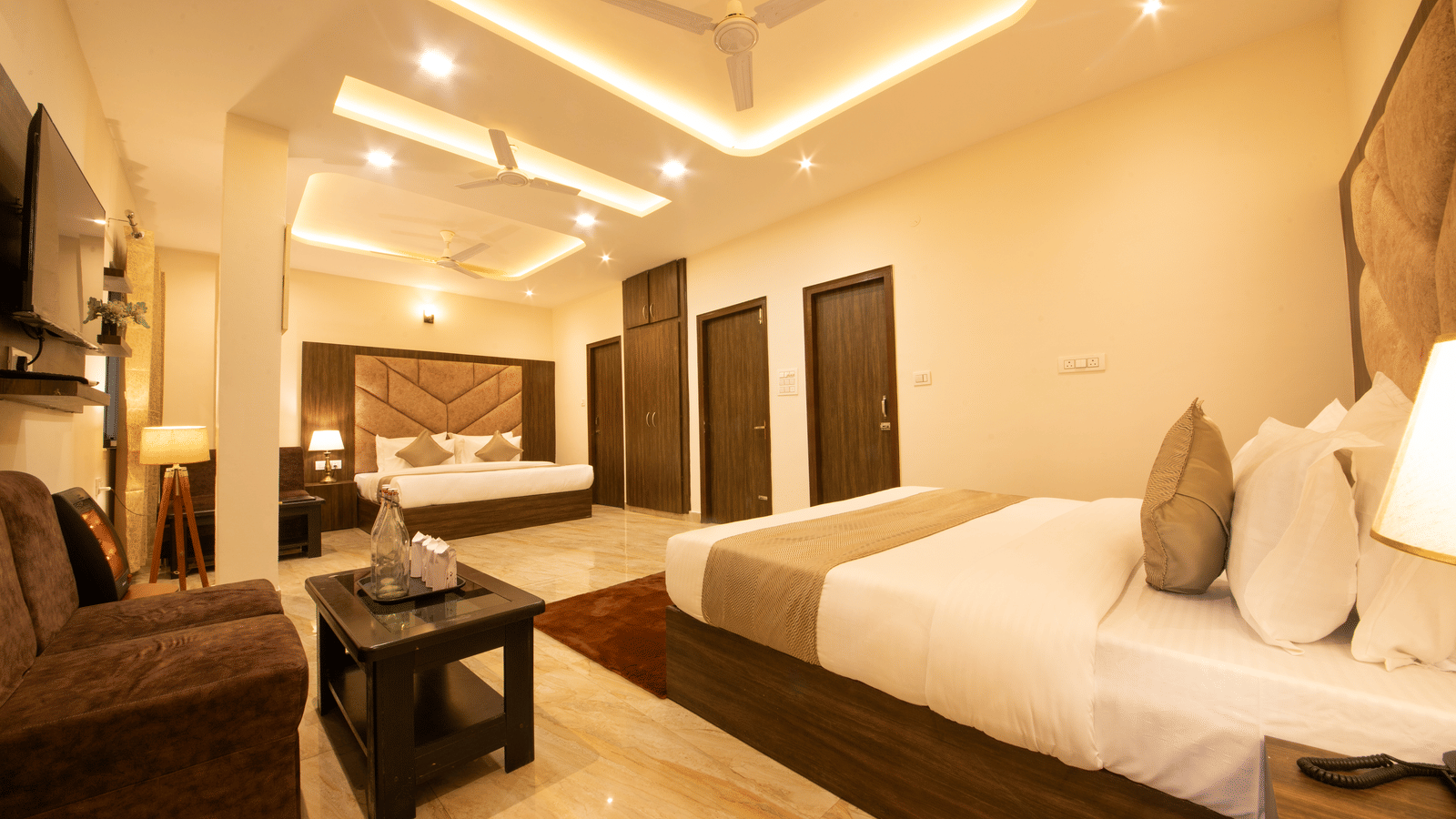 A wide-angle shot of the Family Room featuring a brightly-lit room with 2 double beds and a seating area in the corner.