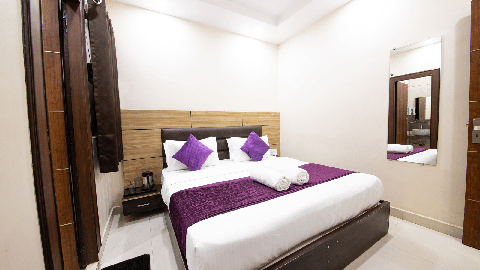 Interior view of a hotel room showing a double bed and reflection in a mirror at Perfectstayz Value Dwarkesh, Haridwar.