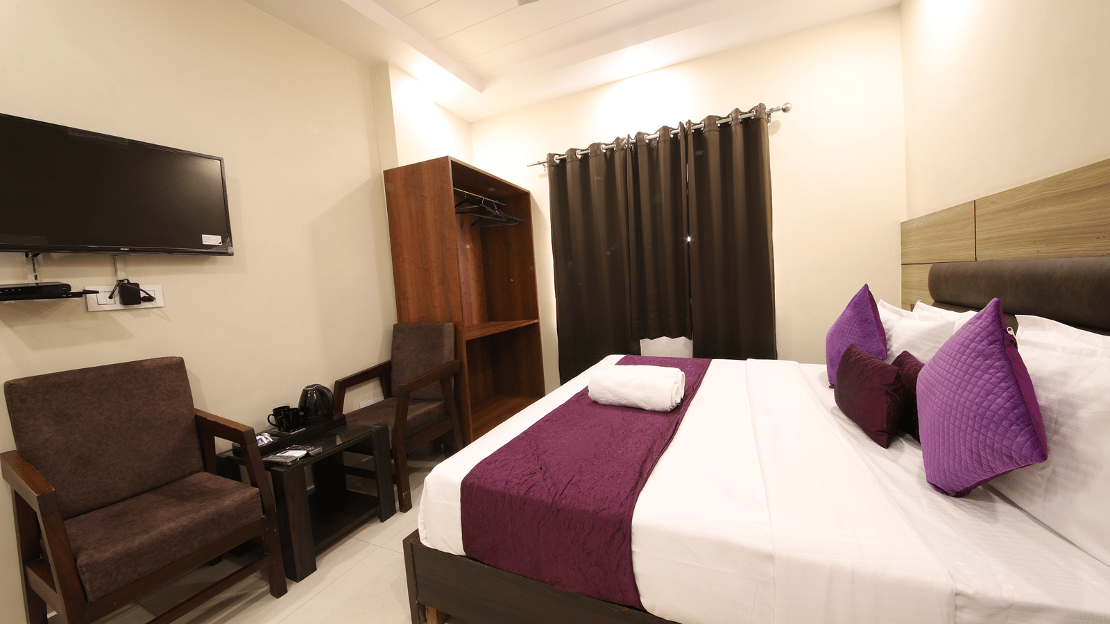 Interior view of a hotel room with 2 beds, a television, and seating at Perfectstayz Value Dwarkesh, Haridwar.