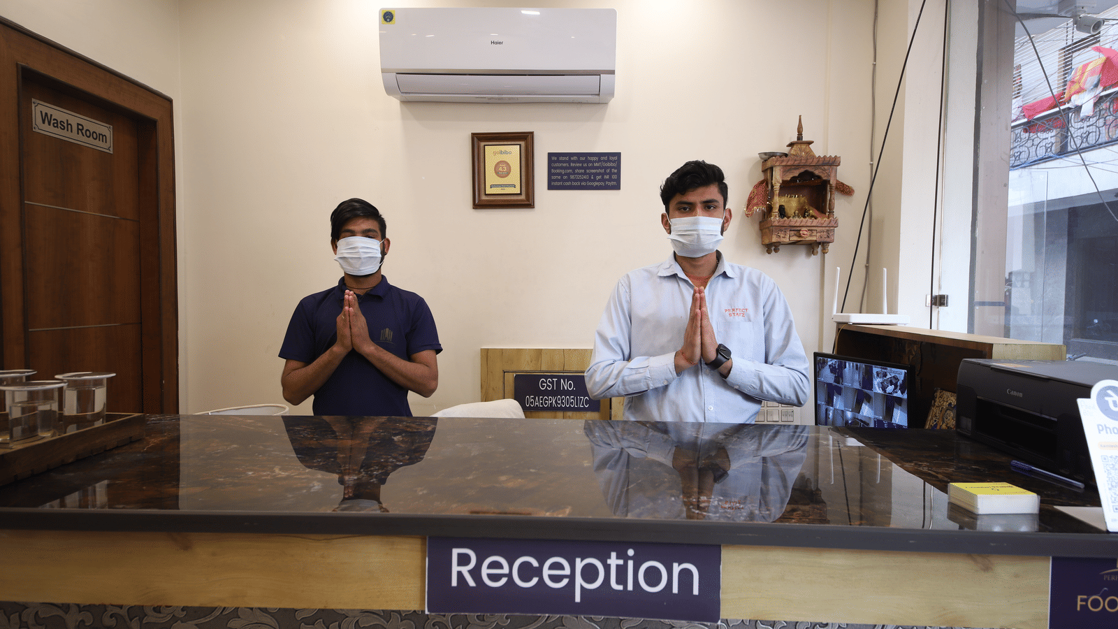 Interior view of staff wearing masks at the reception desk greeting guests at Perfectstayz Value Dwarkesh, Haridwar.