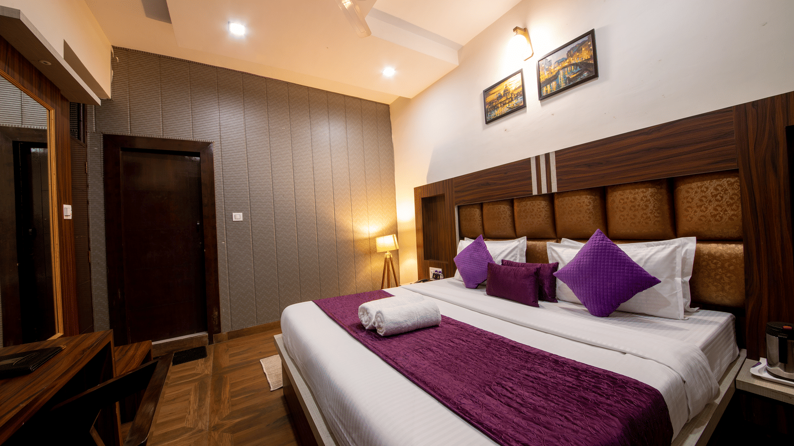 Spacious hotel room with a large bed, dark brown wooden headboard, purple and white bedding, and minimal decor - Perfectstayz Value Grey Castle, Haridwar