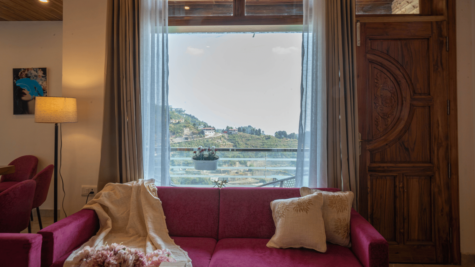 A seating area with a sofa, cushions, and a window showing a hill view at Perfectstayz Value Paradise, Mussoorie.