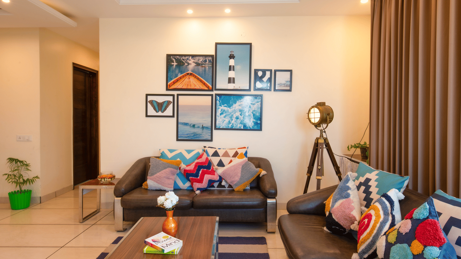 A living room at Perfectstayz Value Shimla (Namah Retreat) with 2 sofas, a coffee table, wall art, a floor lamp, curtains, and an indoor plant.