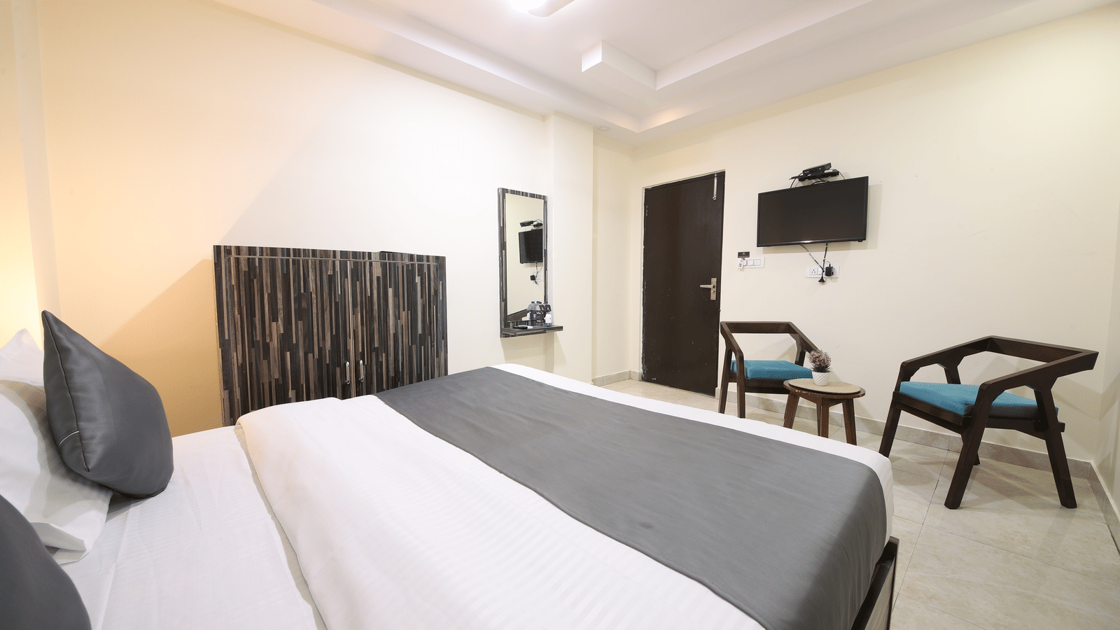 Spacious room with double bed, seating area, and TV - Perfectstayz Value Umra Grace, Haridwar
