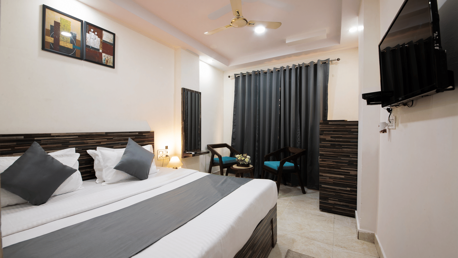 Spacious double bedroom with modern decor, seating area, and ceiling-to-floor curtains - Perfectstayz Value Umra Grace, Haridwar
