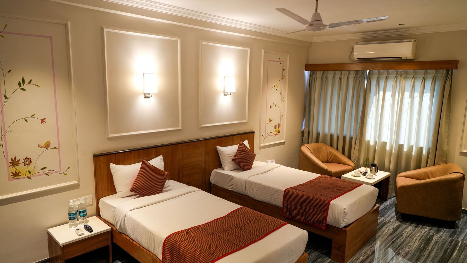 Comfortable twin room with two neatly arranged beds and cosy seating at Pravasa Hotel Kolhapur.