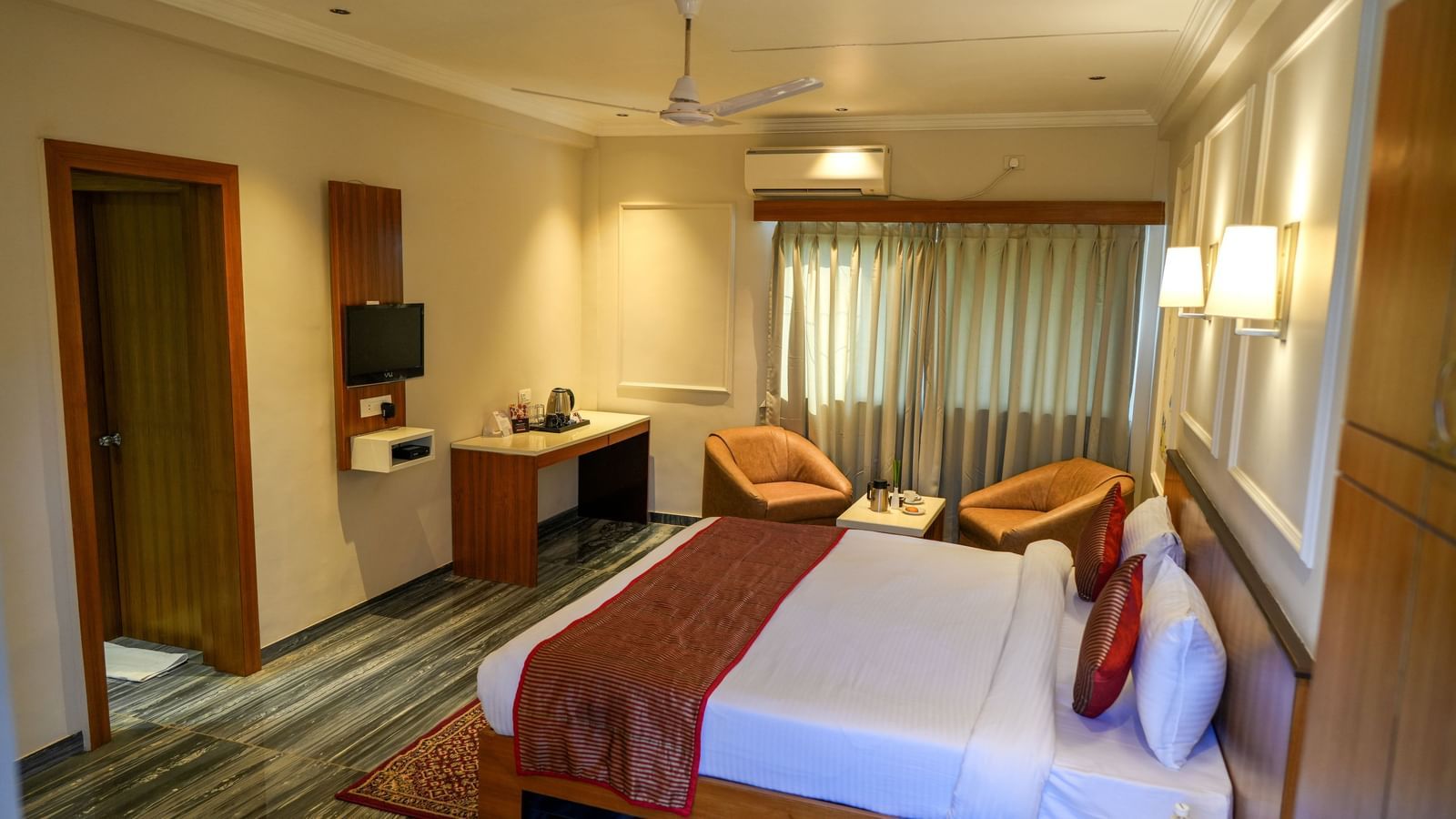 Well-appointed guest room with a king-size bed and seating for relaxation at Pravasa Hotel Kolhapur.