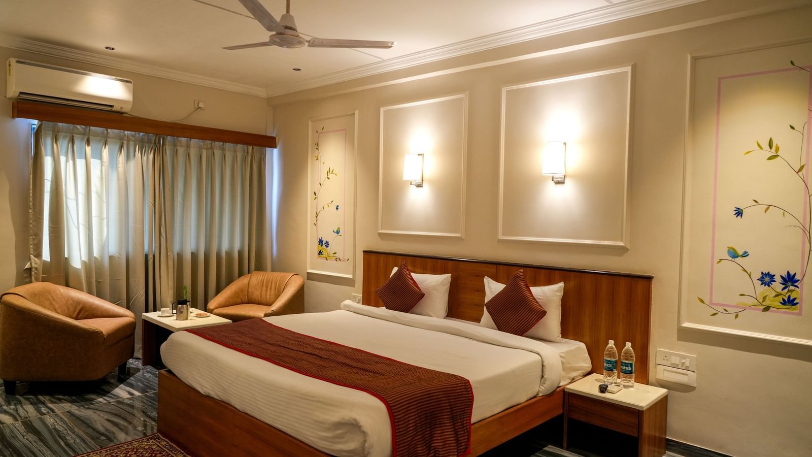 Stylish guest room with a double bed, seating area, and soft lighting at Pravasa Hotel Kolhapur.