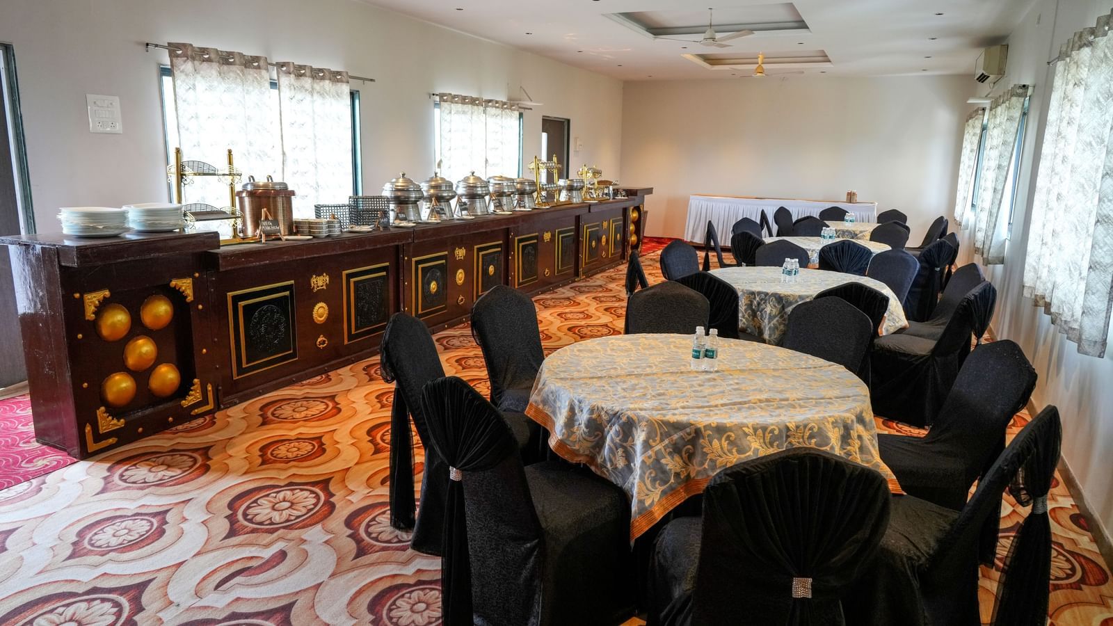 Banquet hall with round tables and elegant seating for gatherings at Pravasa Hotel Kolhapur.