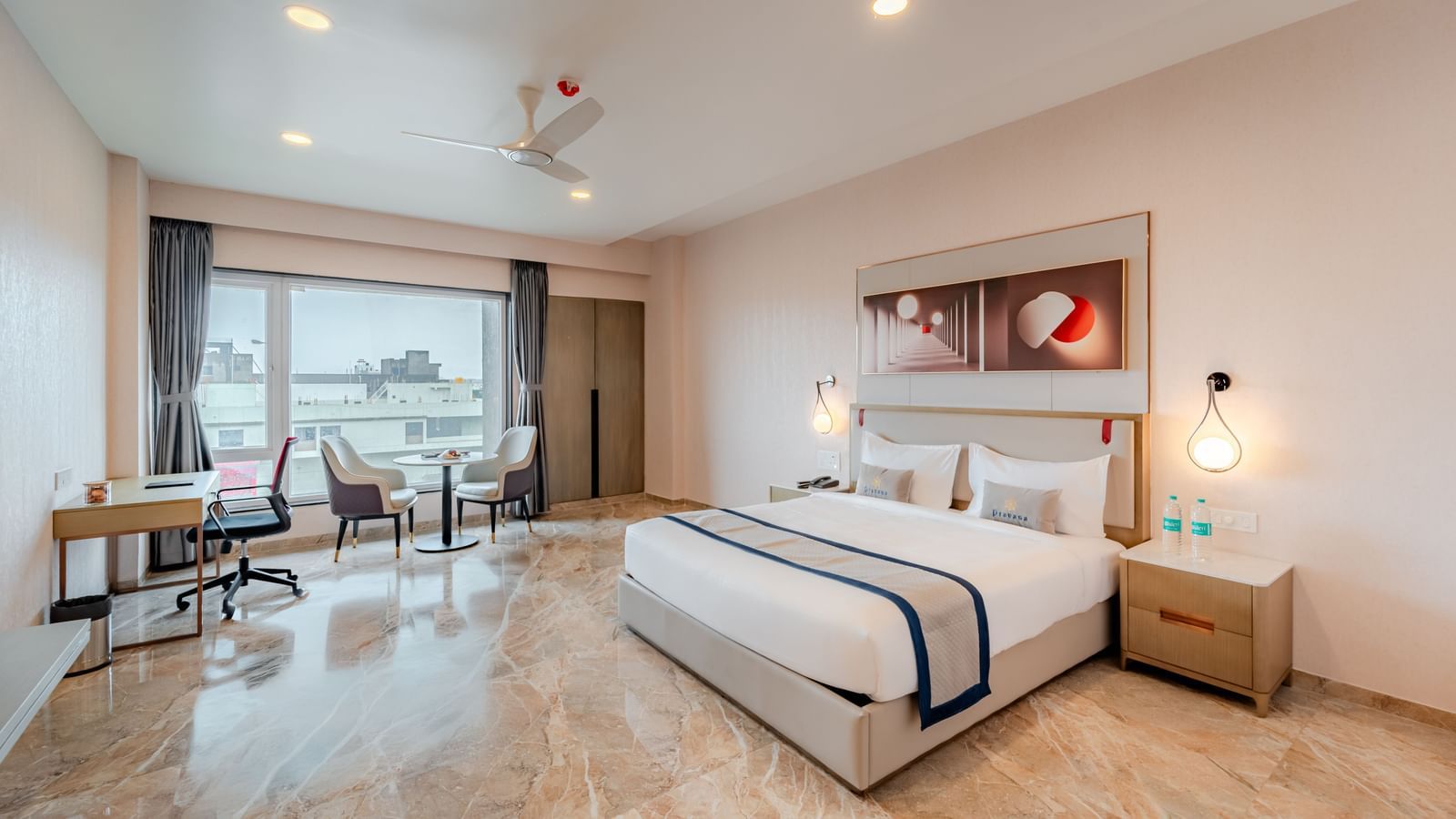 Spacious hotel room featuring a king-size bed, work desk, and city views | Premium Room | Pravasa Hotel, Vijayapura