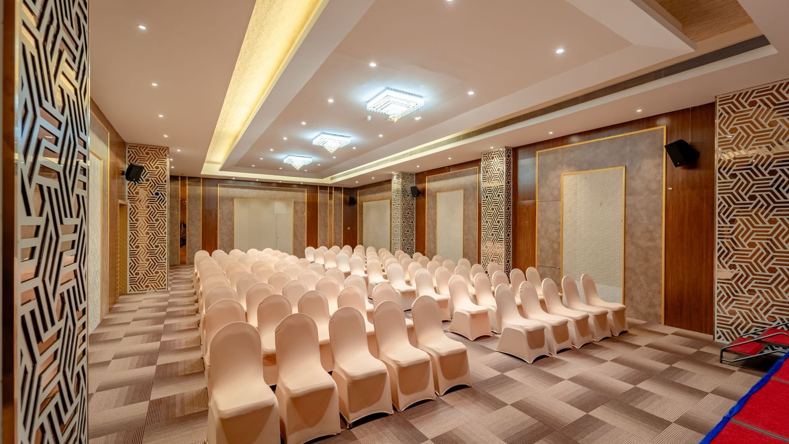 An empty ballroom set up with rows of beige chairs | Meetings & Events | Pravasa Hotel, Vijayapura