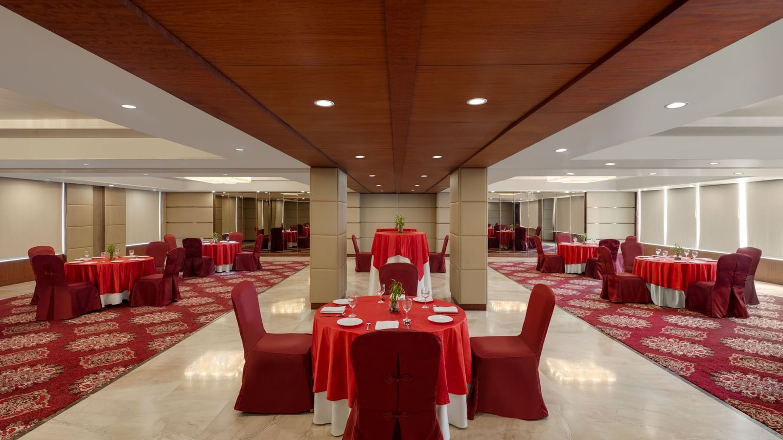 Large banquet hall with red table linens and round seating at Ramada by Wyndham Ghaziabad Vasundhara