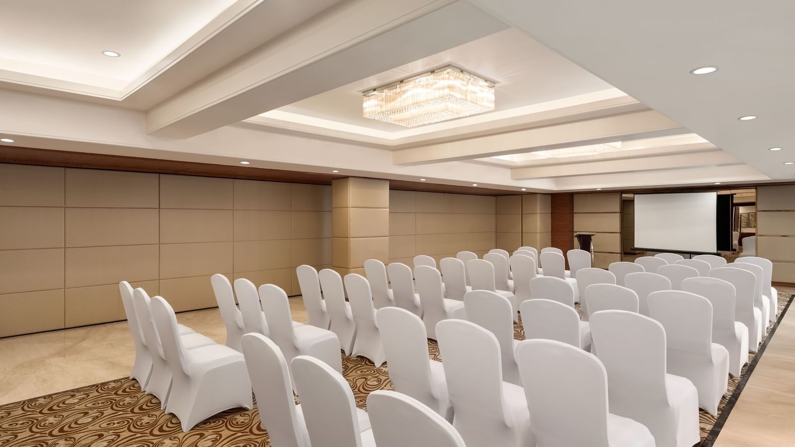 Conference room with white chairs in theater-style seating at Ramada by Wyndham Ghaziabad Vasundhara