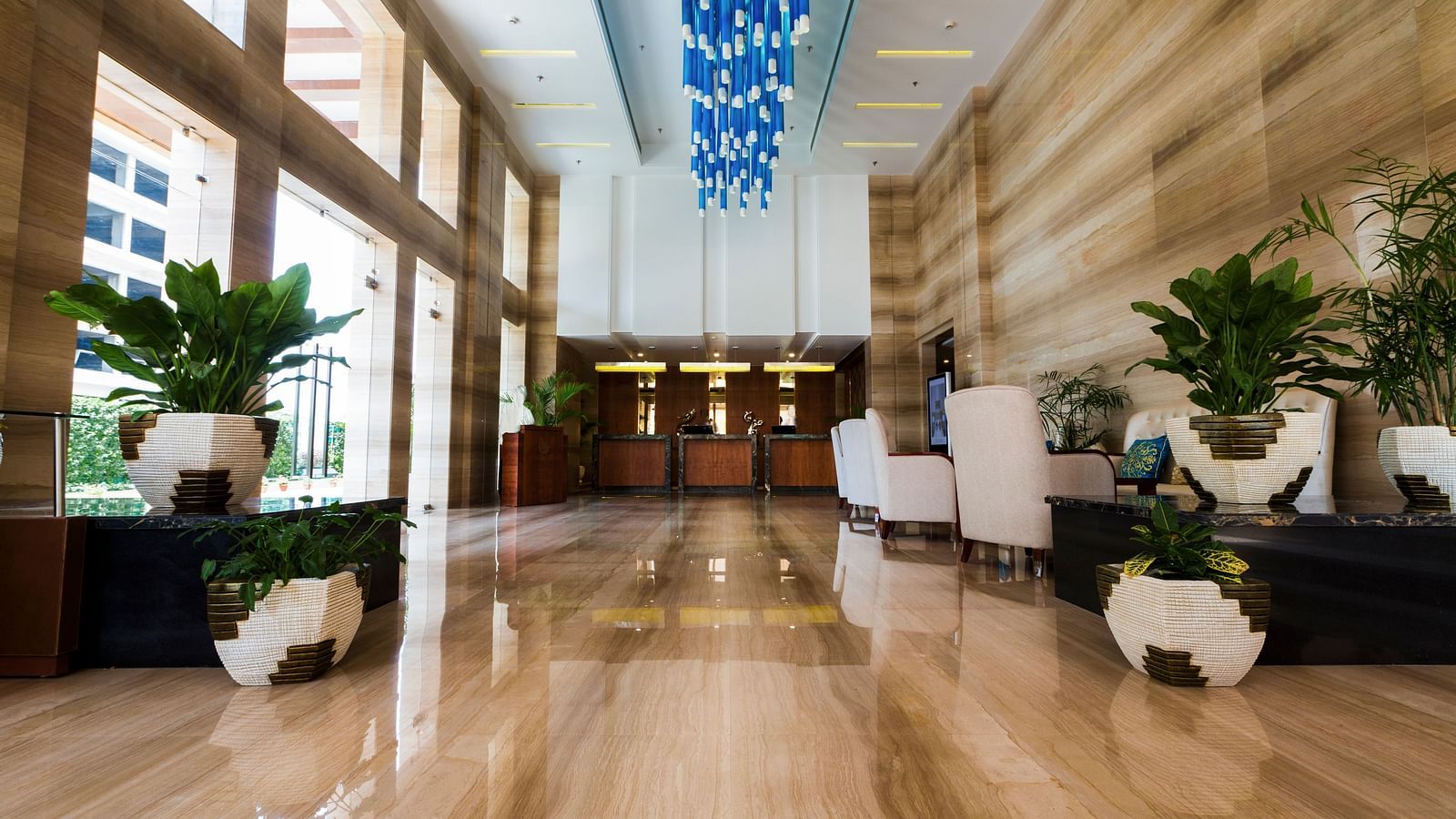 An expansive lobby with ample of natural light coming from outside of the hotel featuring a reception desk at the far end of the lobby - Ramada by Wyndham, Ghaziabad, Vasundhara
