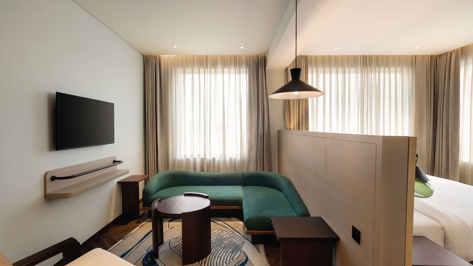 Ramada Encore by Wyndham, Bhiwadi | Hotel room with green couch, bed, TV, and decorative lighting.