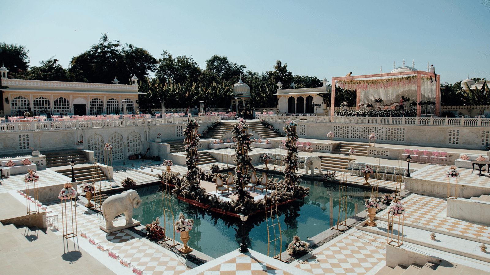 Outdoor poolside area decorated for a wedding celebration with flowers and drapes