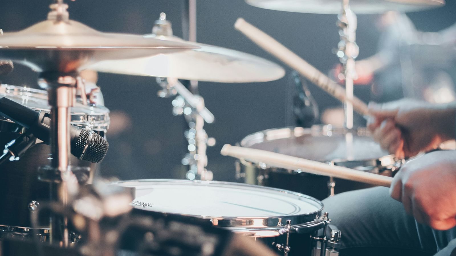 Close-up of a drum kit with cymbals and snare drum, drumsticks in motion.