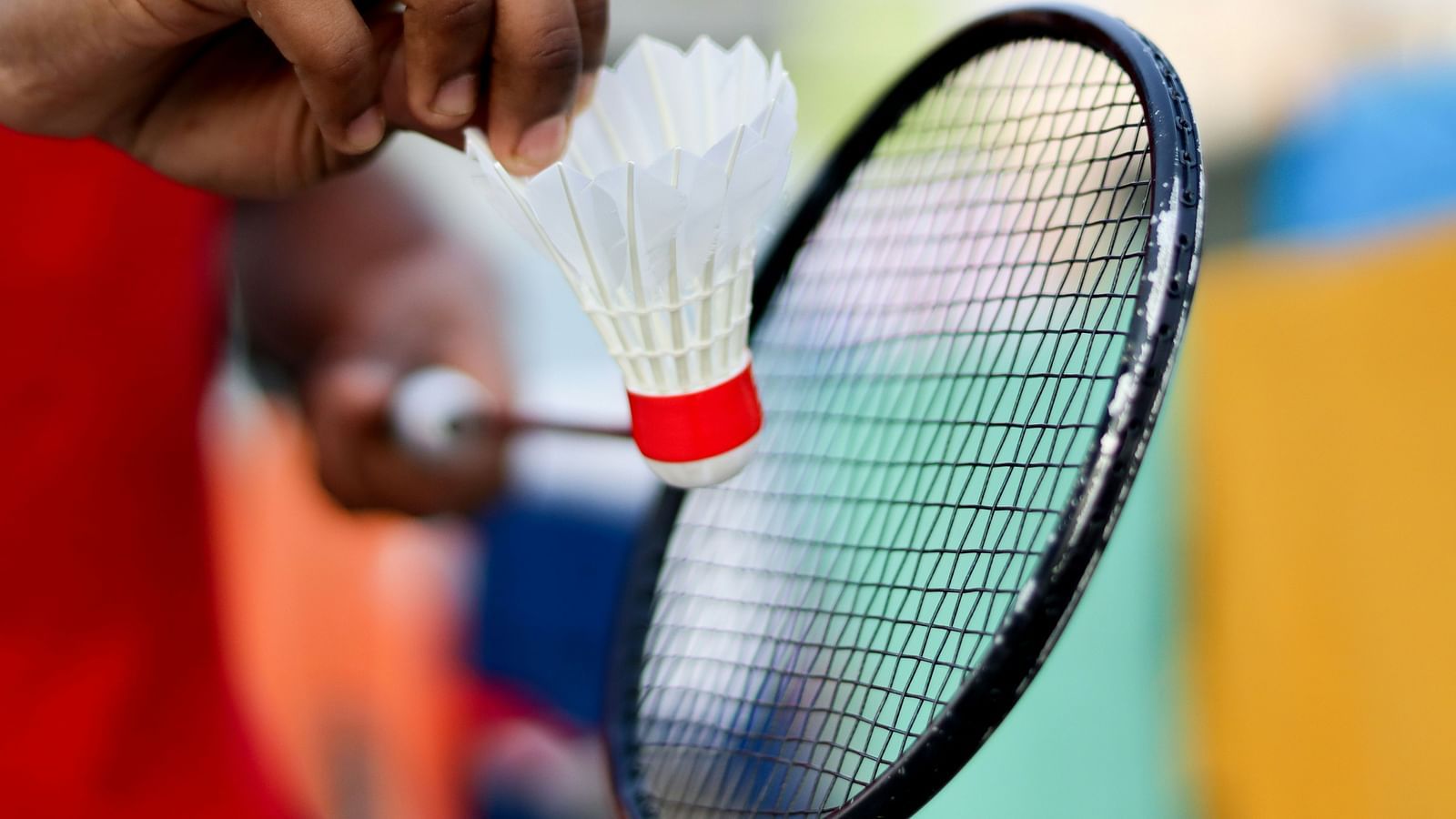 Image of person holding a racquet in one hand and shuttlecock in another