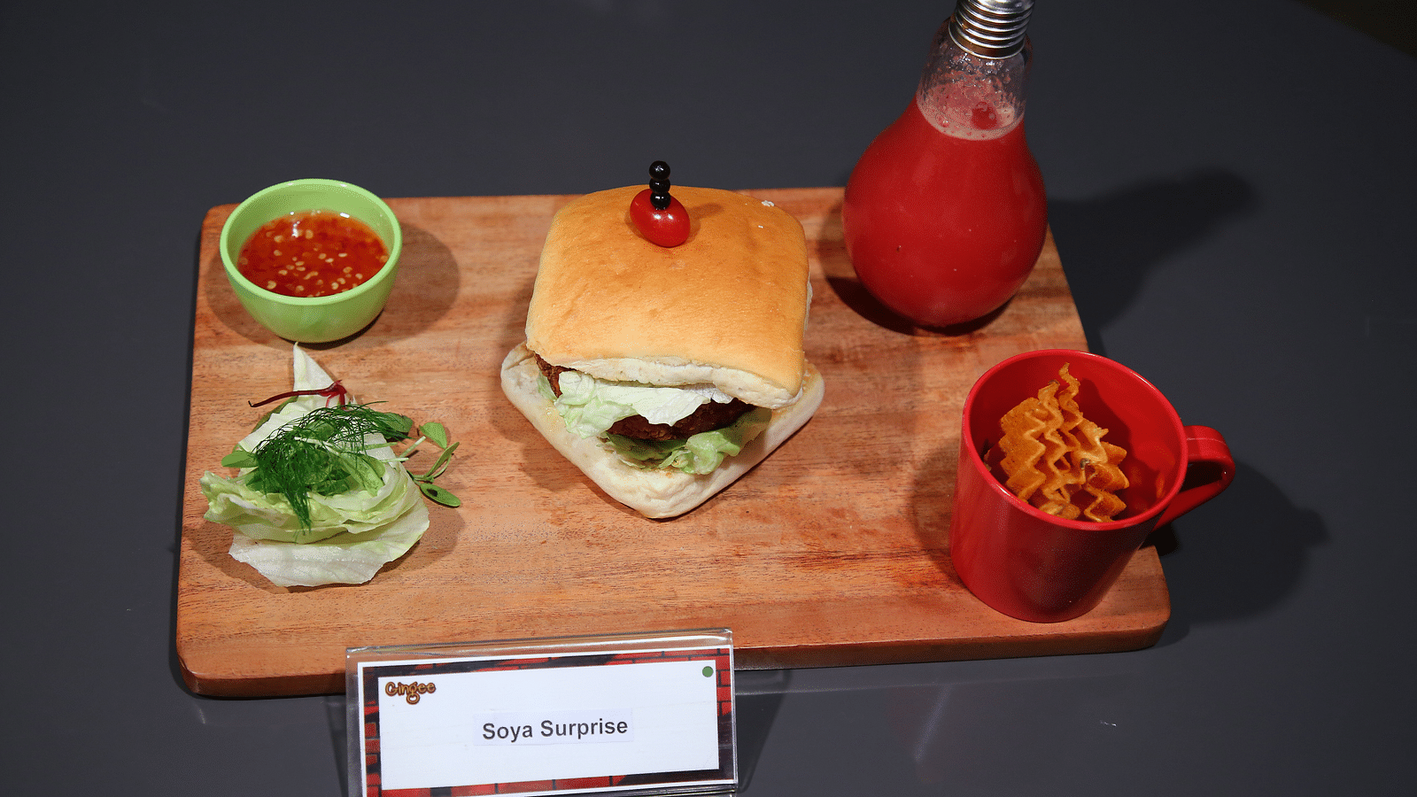 A burger, fries, and a drink served on a wooden board.