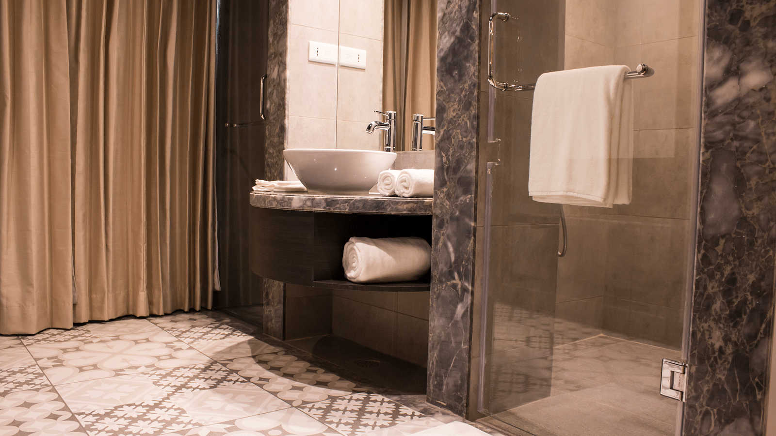 Wide view shot of a bathroom with a sink, mirrors  and towels | Regency Tirunelveli By GRT Hotels