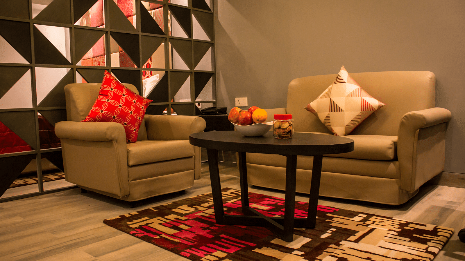 Image of sofa and table kept inside a hotel room Image of a room with a bed and  pillows arranged on it  along with  a balcony | Regency Tirunelveli By GRT Hotels
