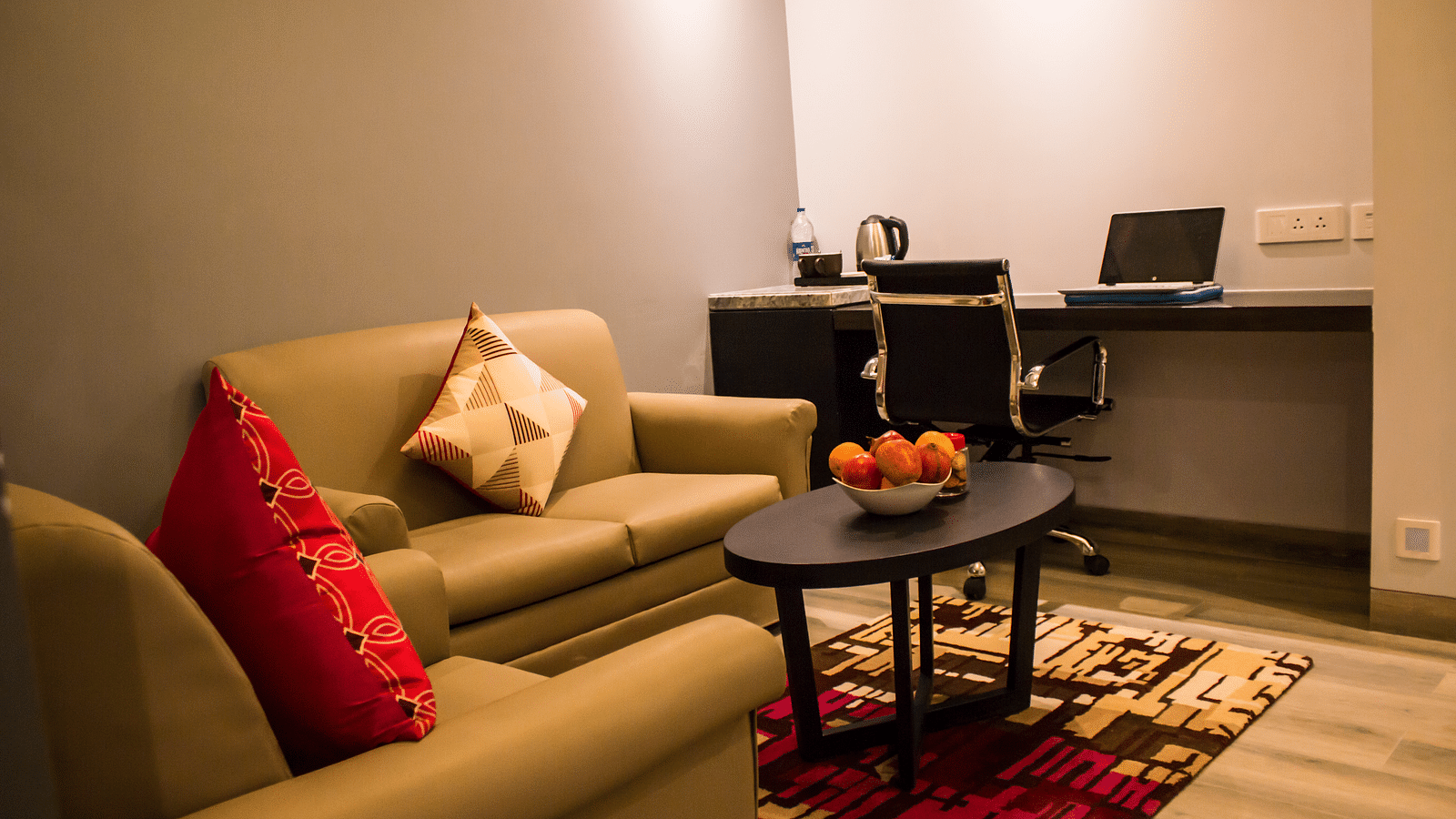 side view image of sofa and table kept inside a hotel room Image of a room with a bed and  pillows arranged on it  along with  a balcony | Regency Tirunelveli By GRT Hotels
